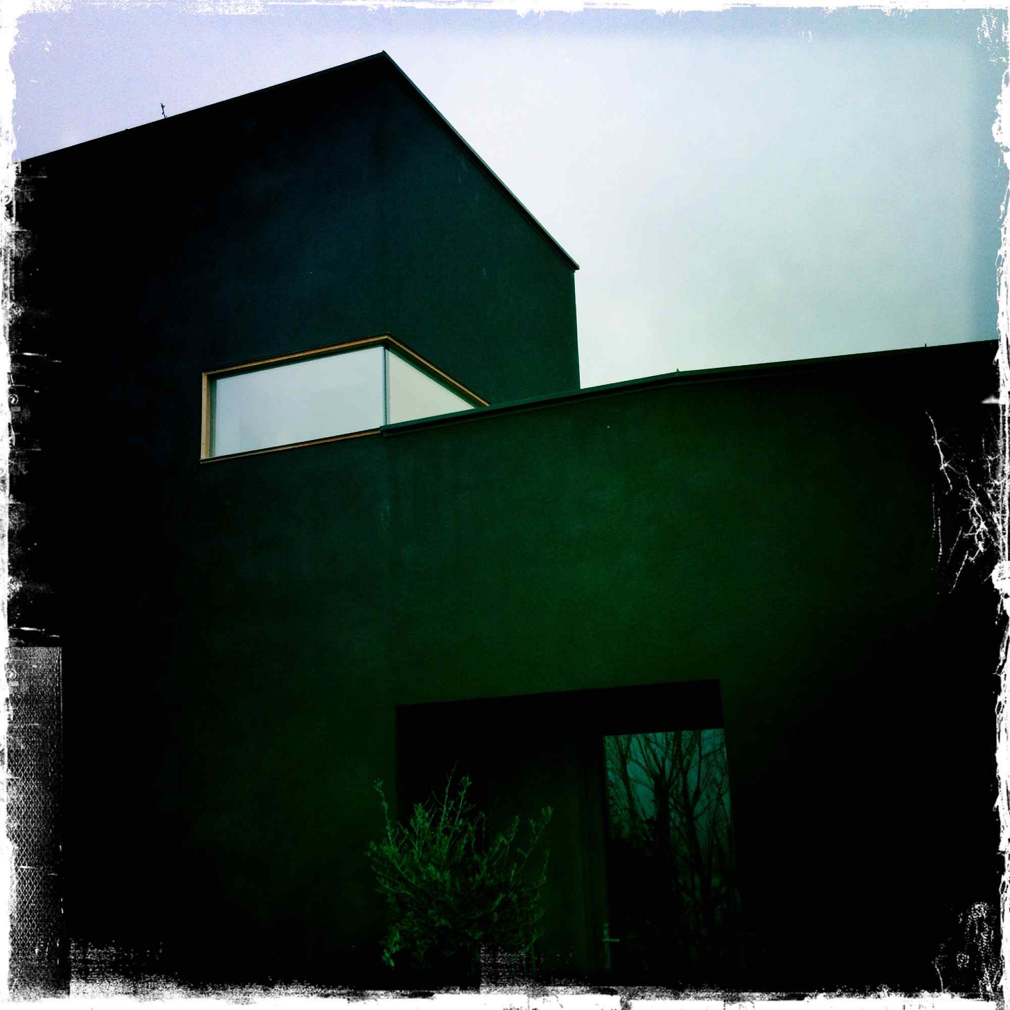 Dunkle Gebäudeecke mit kleinem Oberlicht und Schattenwurf