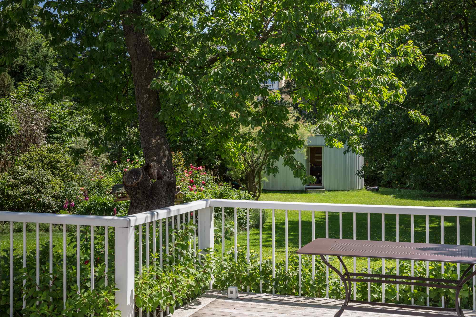 Sitzplatz im Garten mit Geländer und Rasenfläche