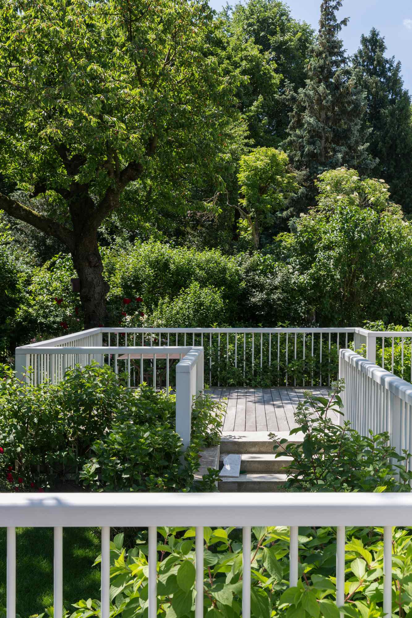 Terrasse mit weißem Geländer und Sitzbereich im Grünen