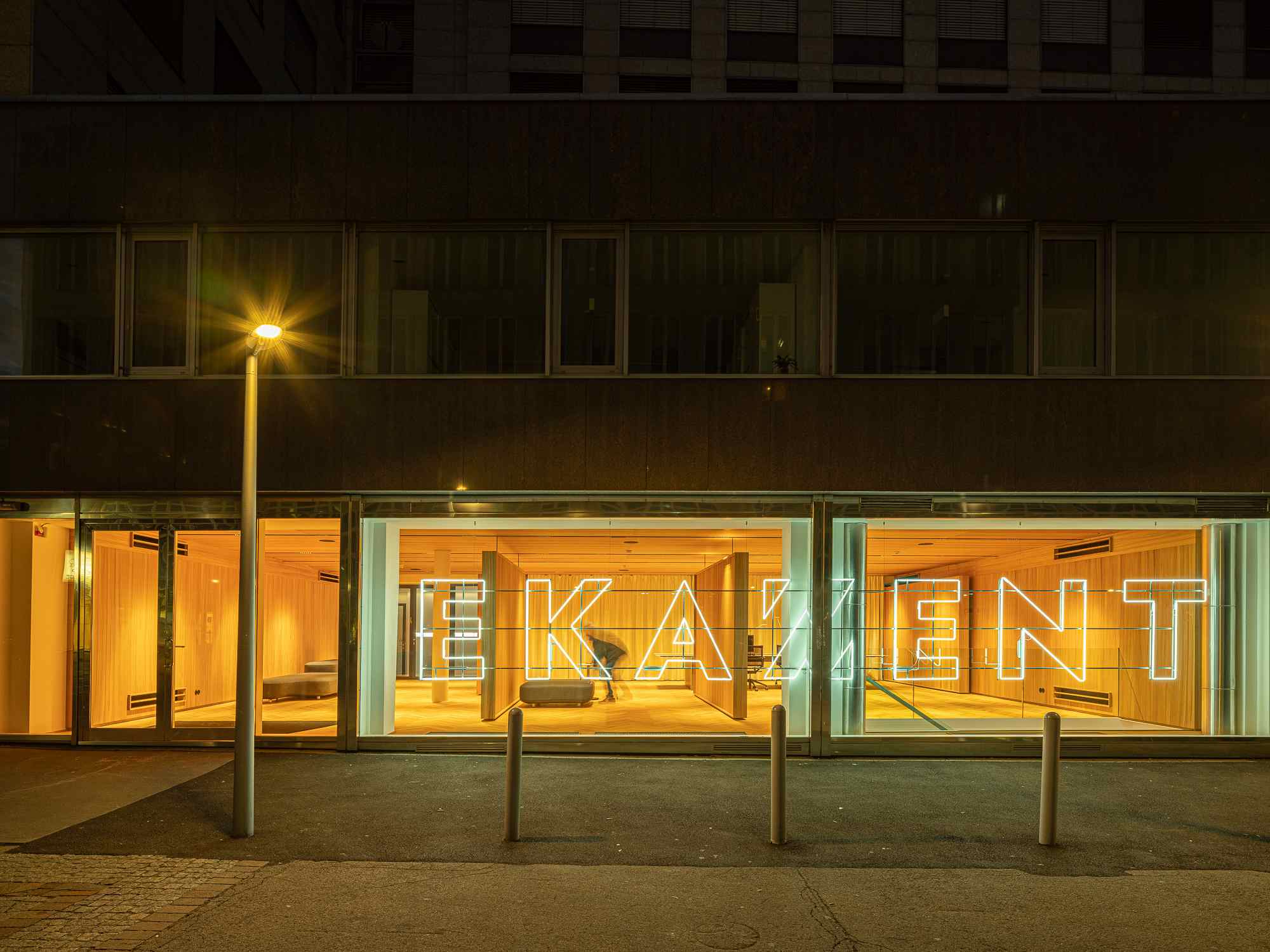 Nachtansicht mit beleuchtetem Schaufenster und orangener Gestaltung