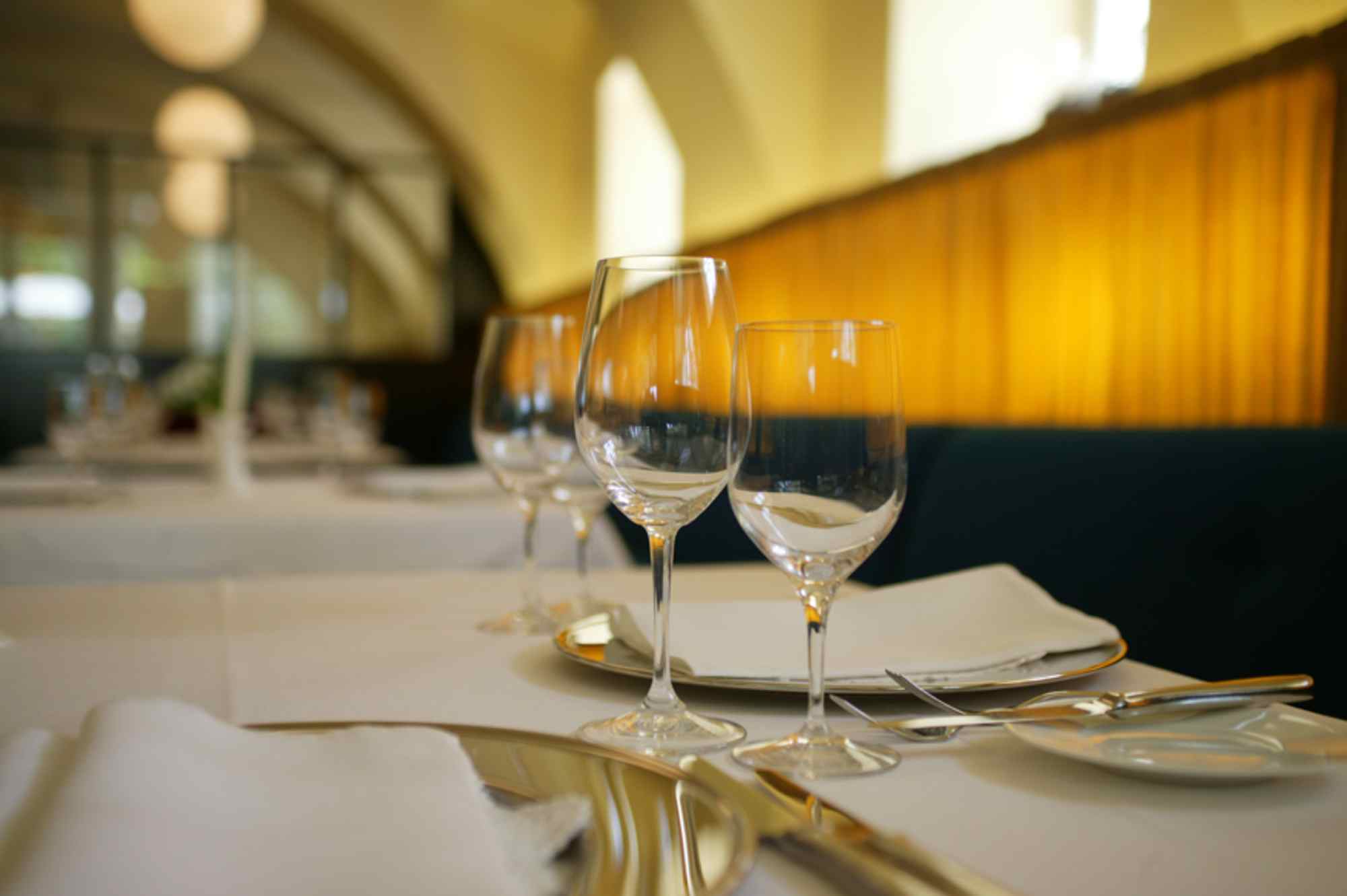 Nahaufnahme eines gedeckten Tisches mit Gläsern und Besteck, weicher Fokus