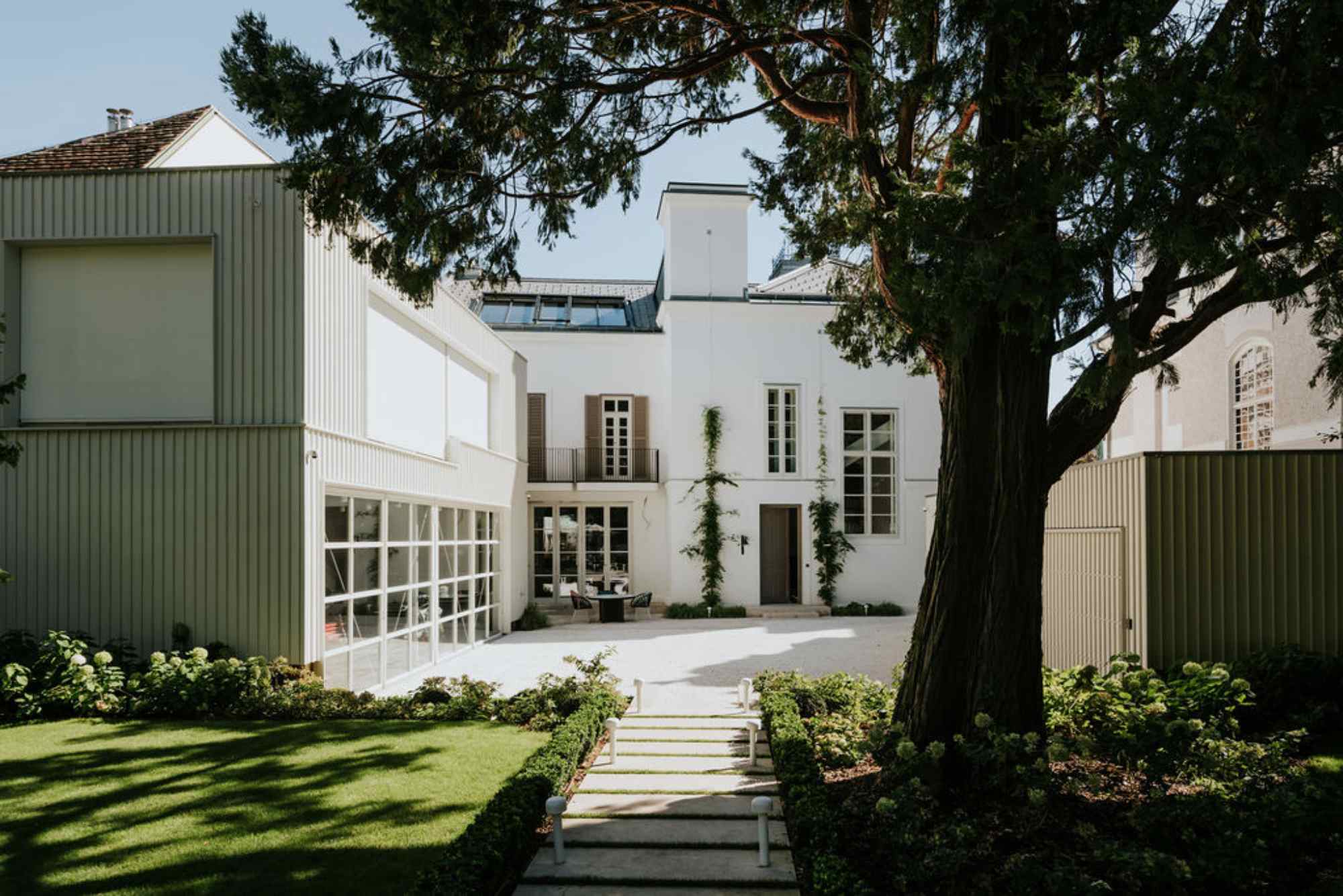 Gartenblick mit zentralem Baum zwischen Gebäudeteilen