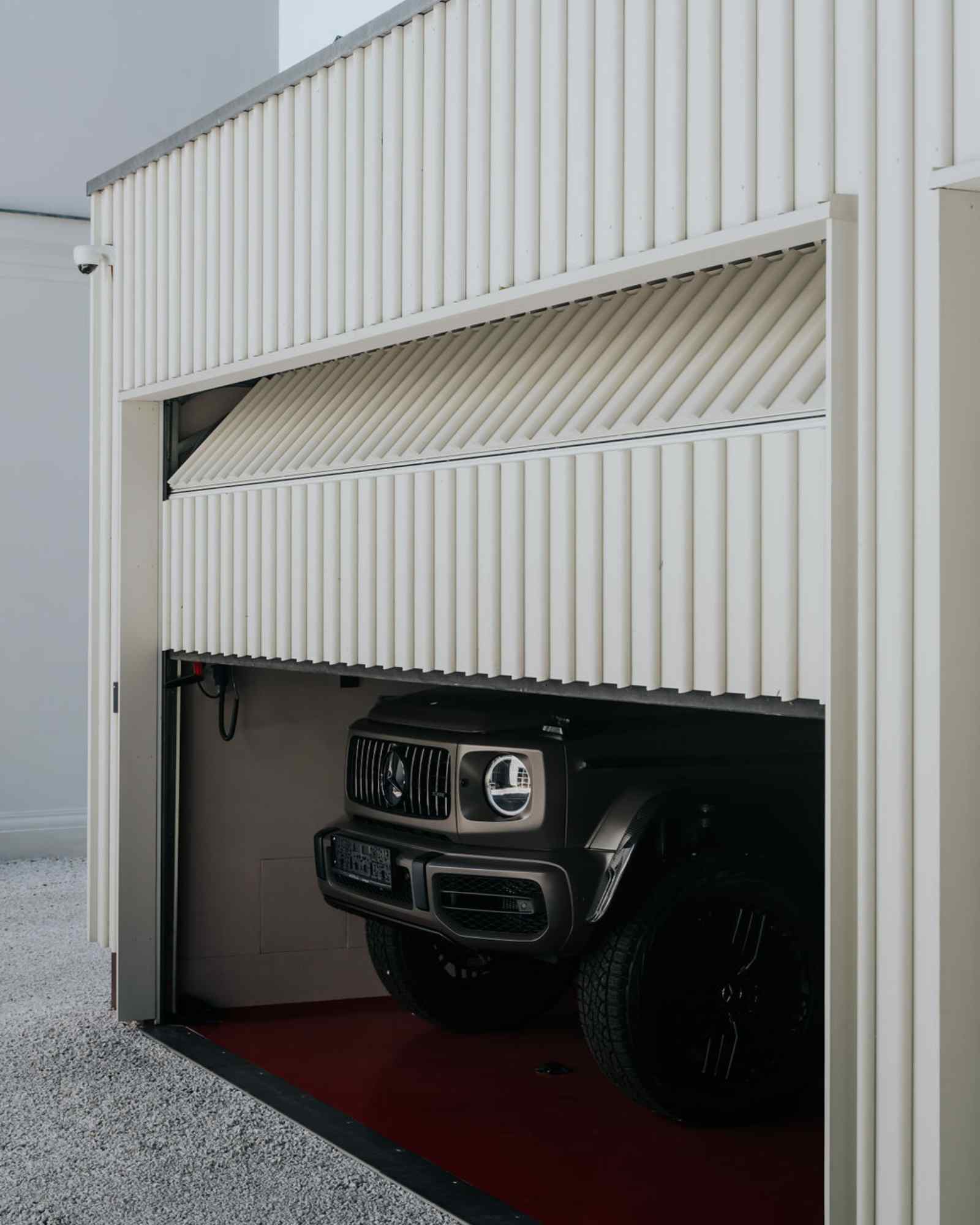 SUV in geöffneter Garage mit weißer Lamellenverkleidung