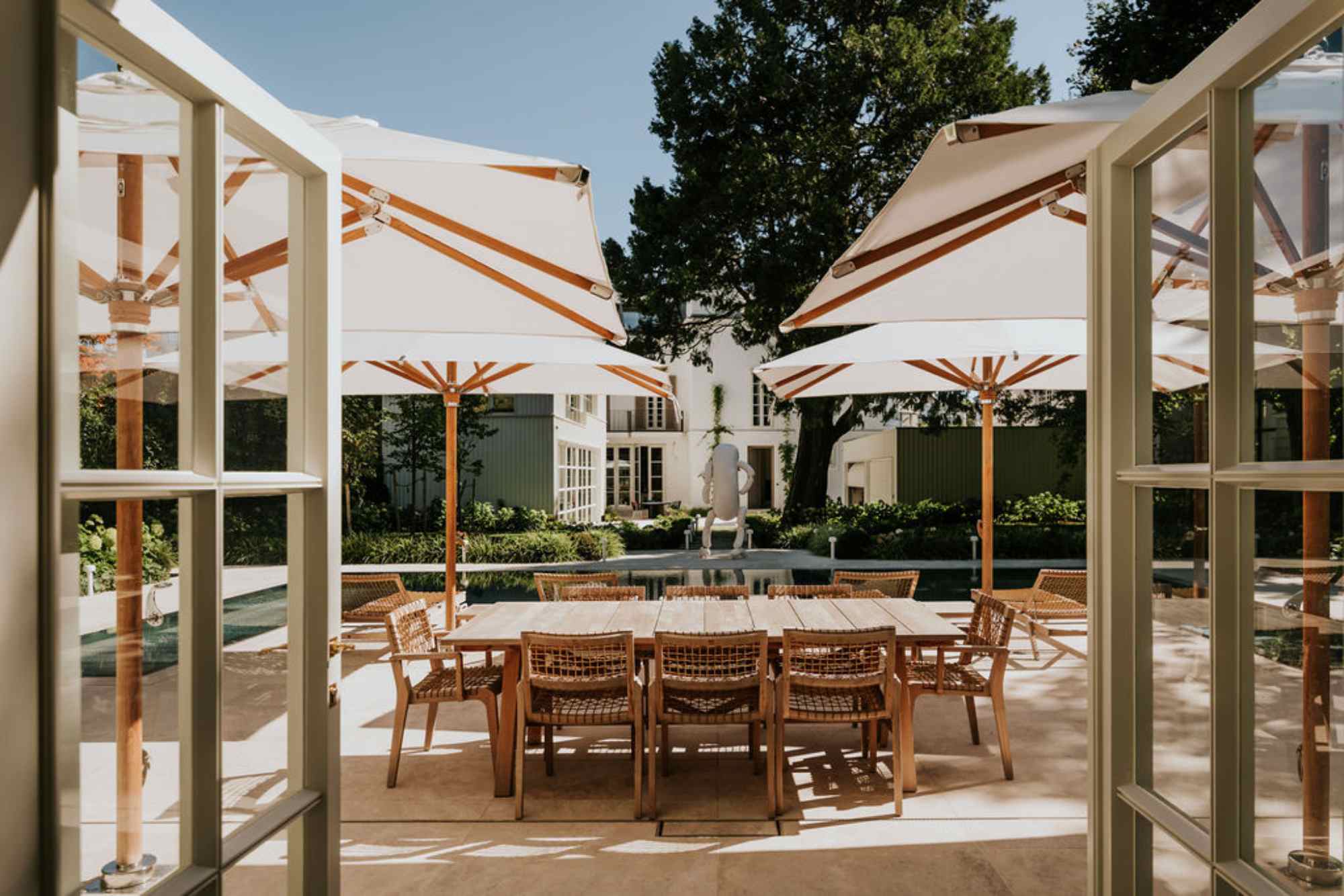 Terrasse mit Holztisch unter heller Pergola