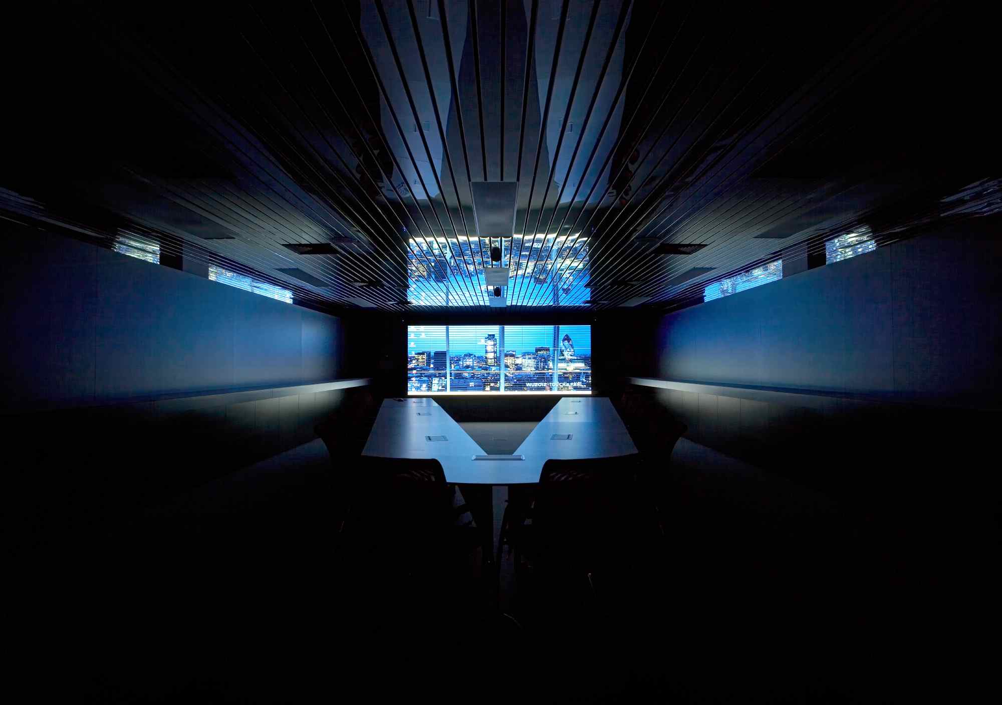 Dunkler Besprechungsraum mit großem Monitor und futuristischer Beleuchtung