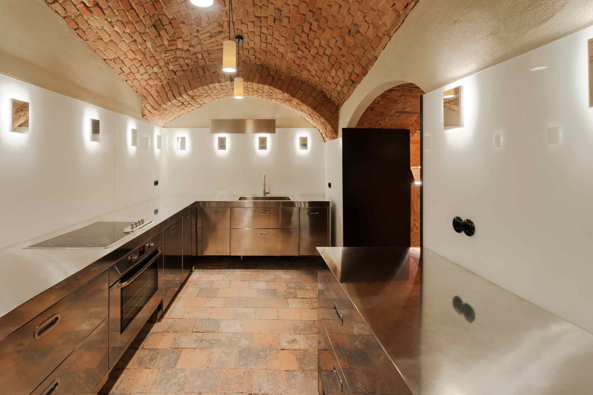 Gewölbekeller mit Backstein-Decke und langem Holztisch im Vordergrund