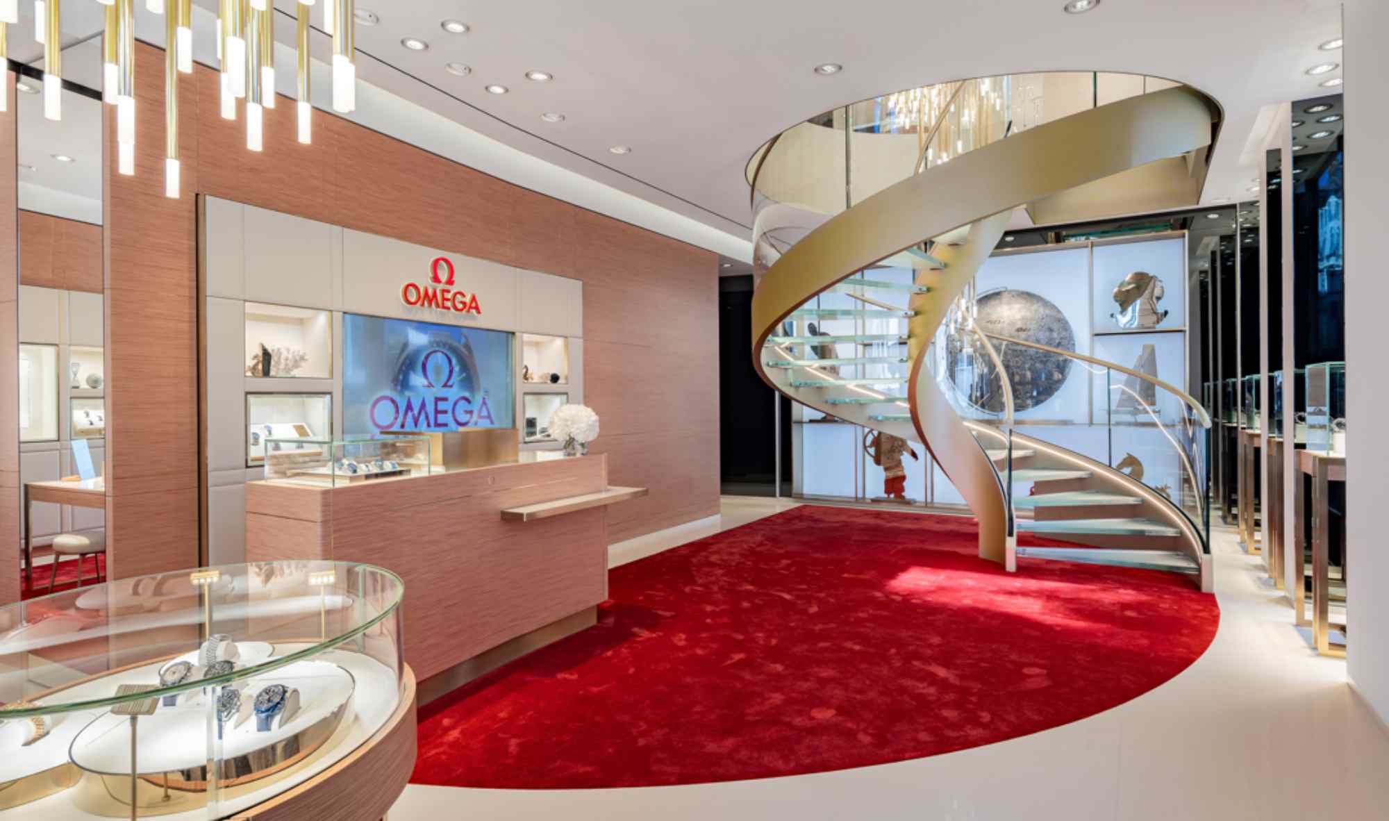 Innenaufnahme der Boutique mit geschwungener Treppe, roten Teppichen und modernen Vitrinen.