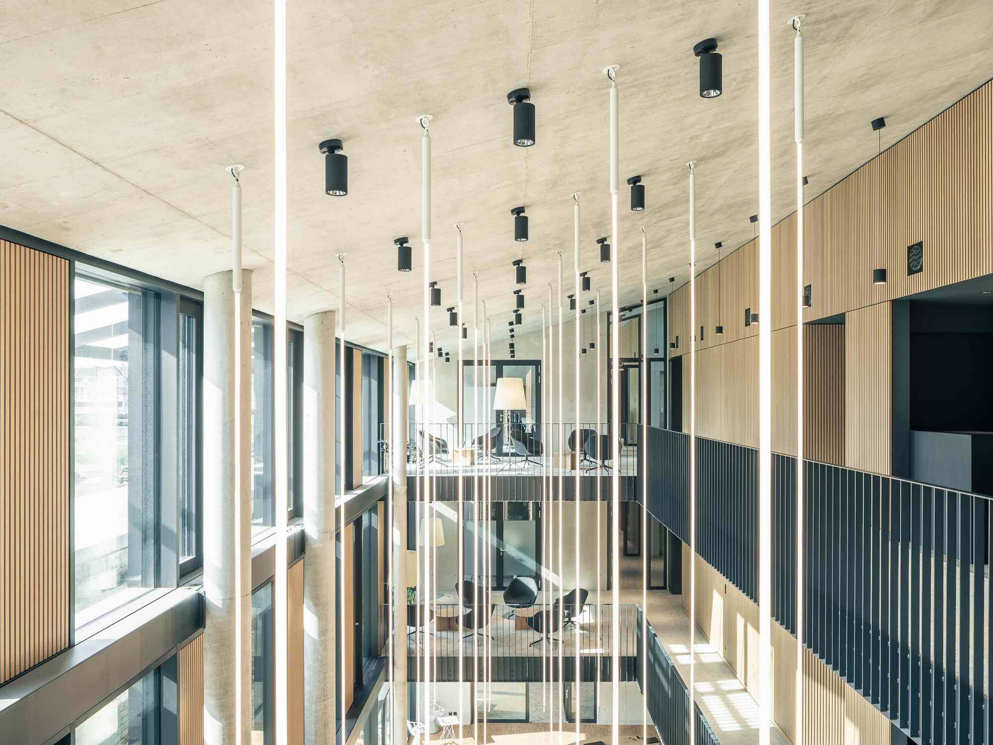 Vertikaler Blick in das mehrstöckige Atrium mit hängenden Lichtleisten und offenen Galerien.