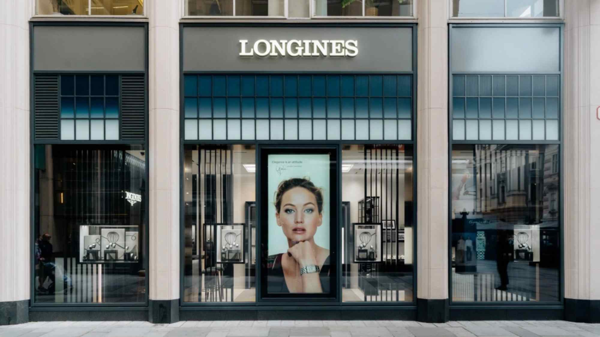 Frontalansicht der Longines-Boutique mit großem Werbeposter in der Mitte und klassischer Fassadengestaltung.