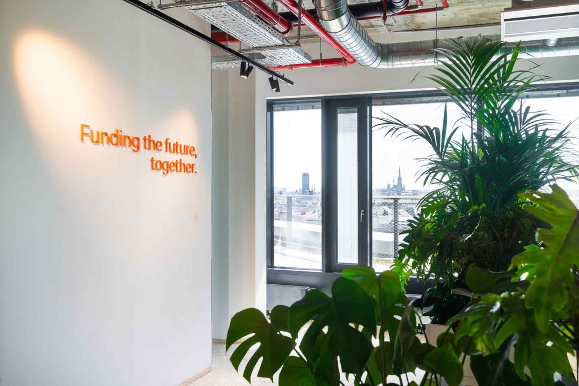 Slogan-Wand mit Pflanzen im Vordergrund.