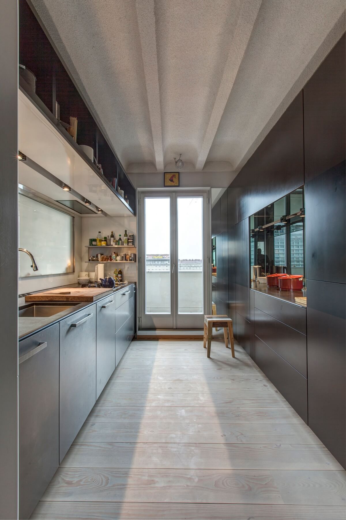 Schmale Küche mit Fenster am Ende und hellem Boden.