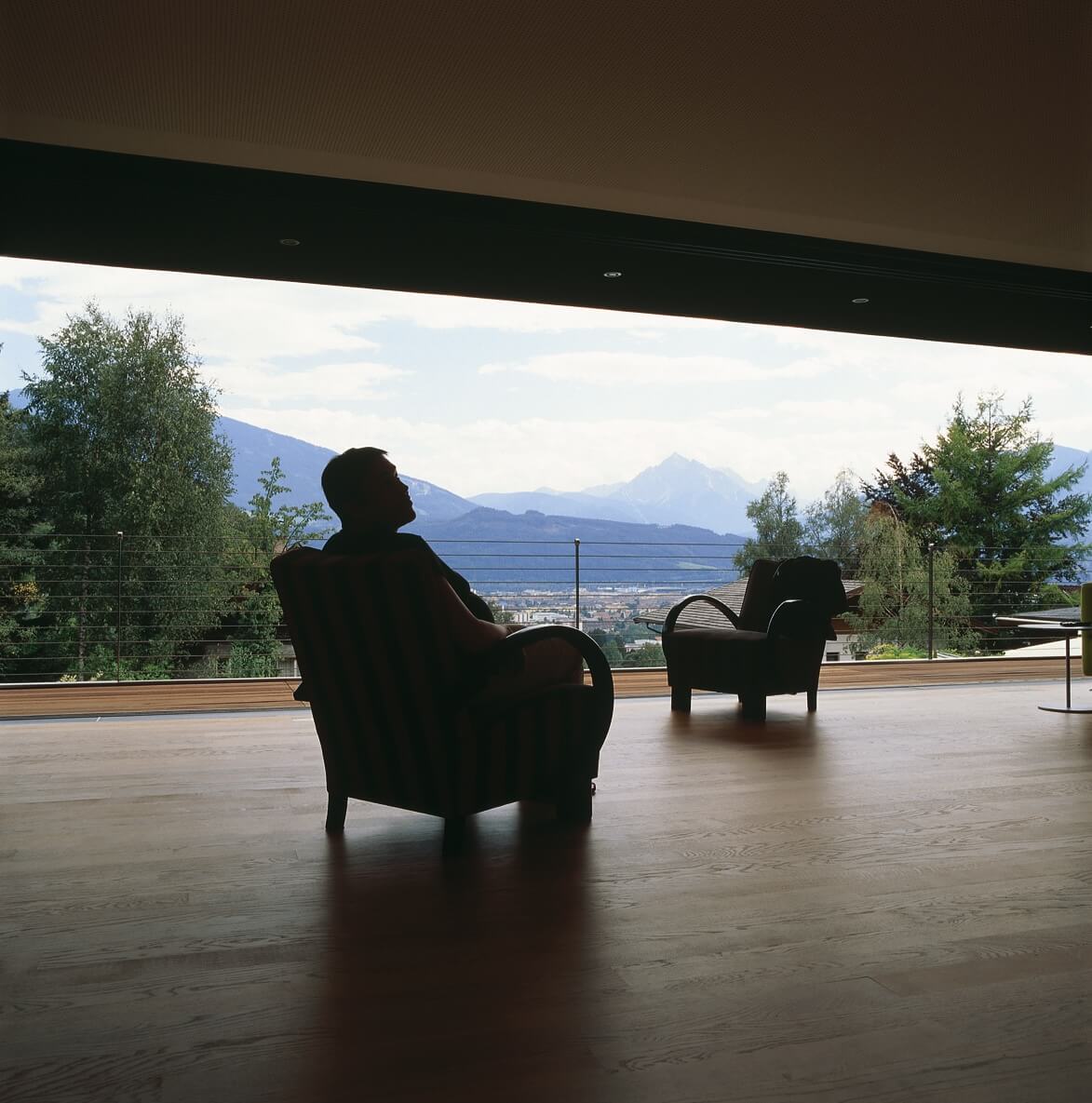 Person sitzt auf Stuhl auf Terrasse mit Ausblick