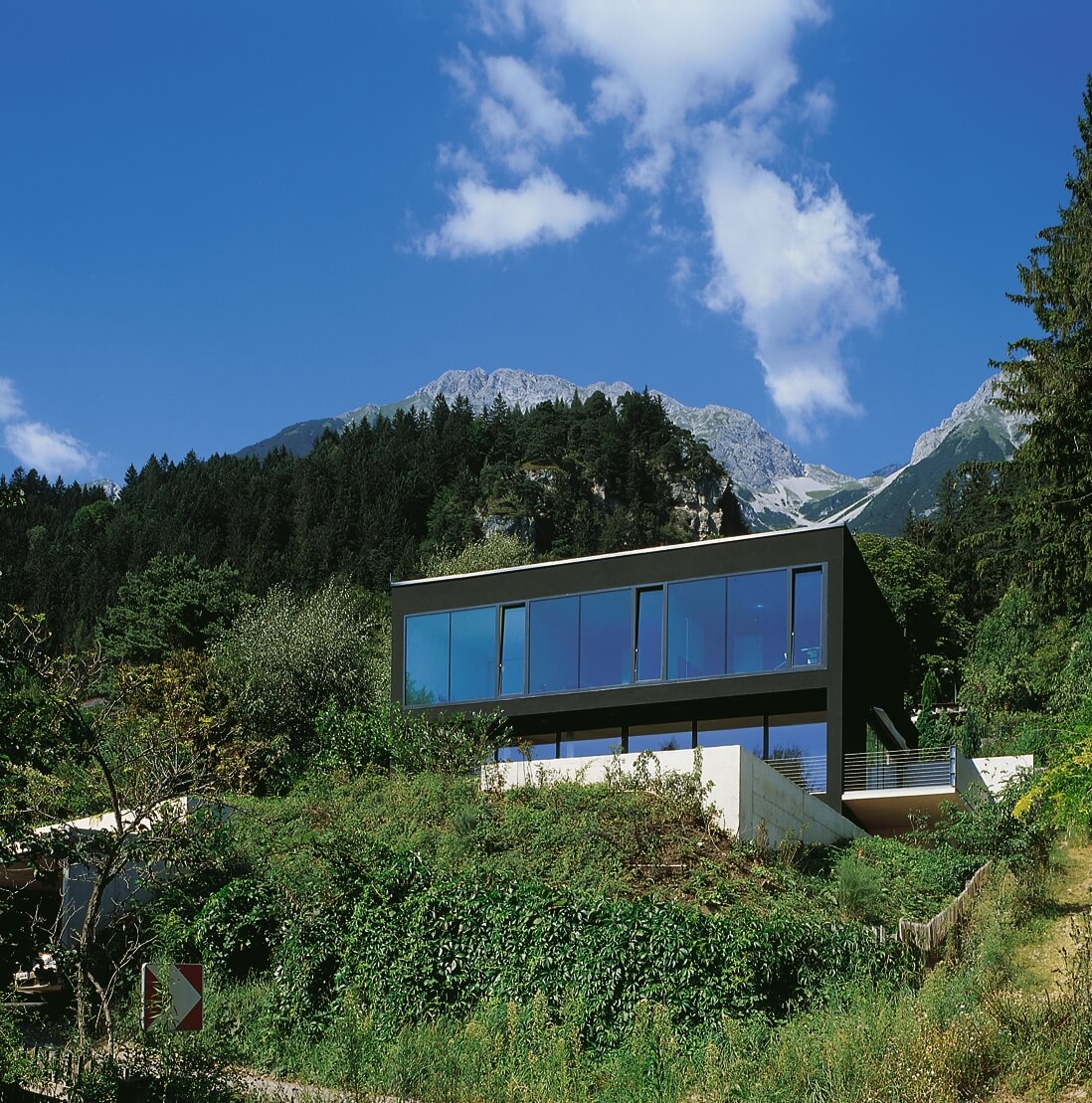 Haus eingebettet in grüne Hanglandschaft.