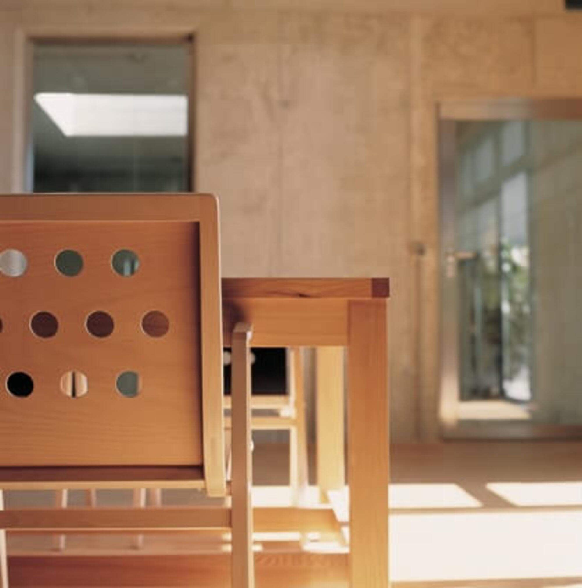 Holzstuhl vor Wand mit Lochmuster.