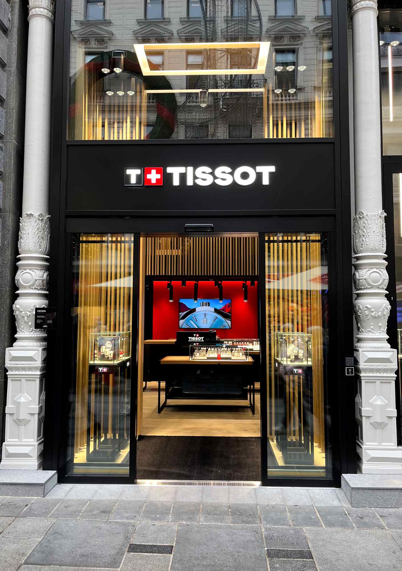 Frontalansicht der Tissot-Boutique mit beleuchtetem Eingang und goldfarbenen Akzenten im modernen Design.