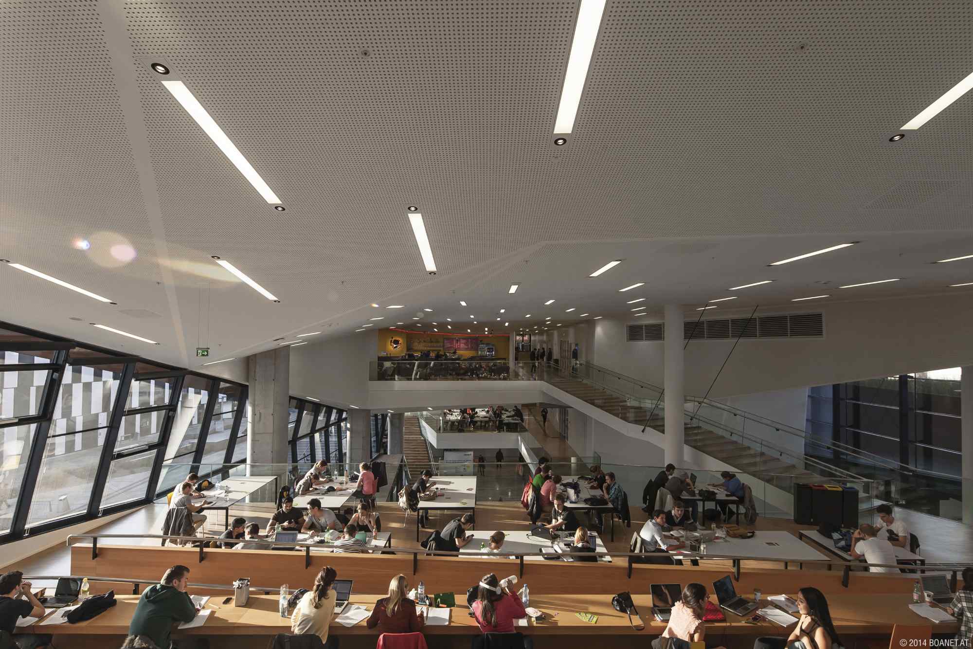 Innenaufnahme des großzügigen Lernbereichs mit Studierenden und Sitzplätzen auf mehreren Ebenen.