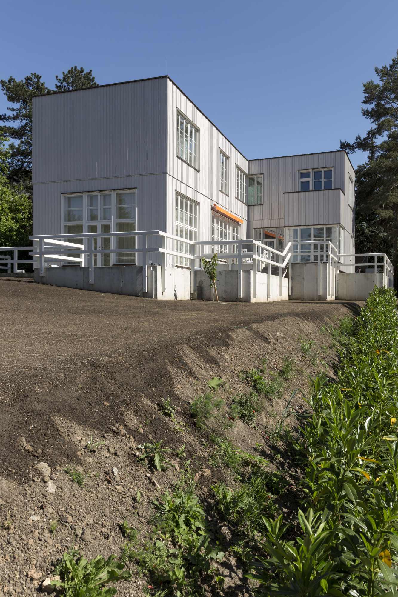 Seitenansicht der Villa mit Holzverschalung und Gartenfläche