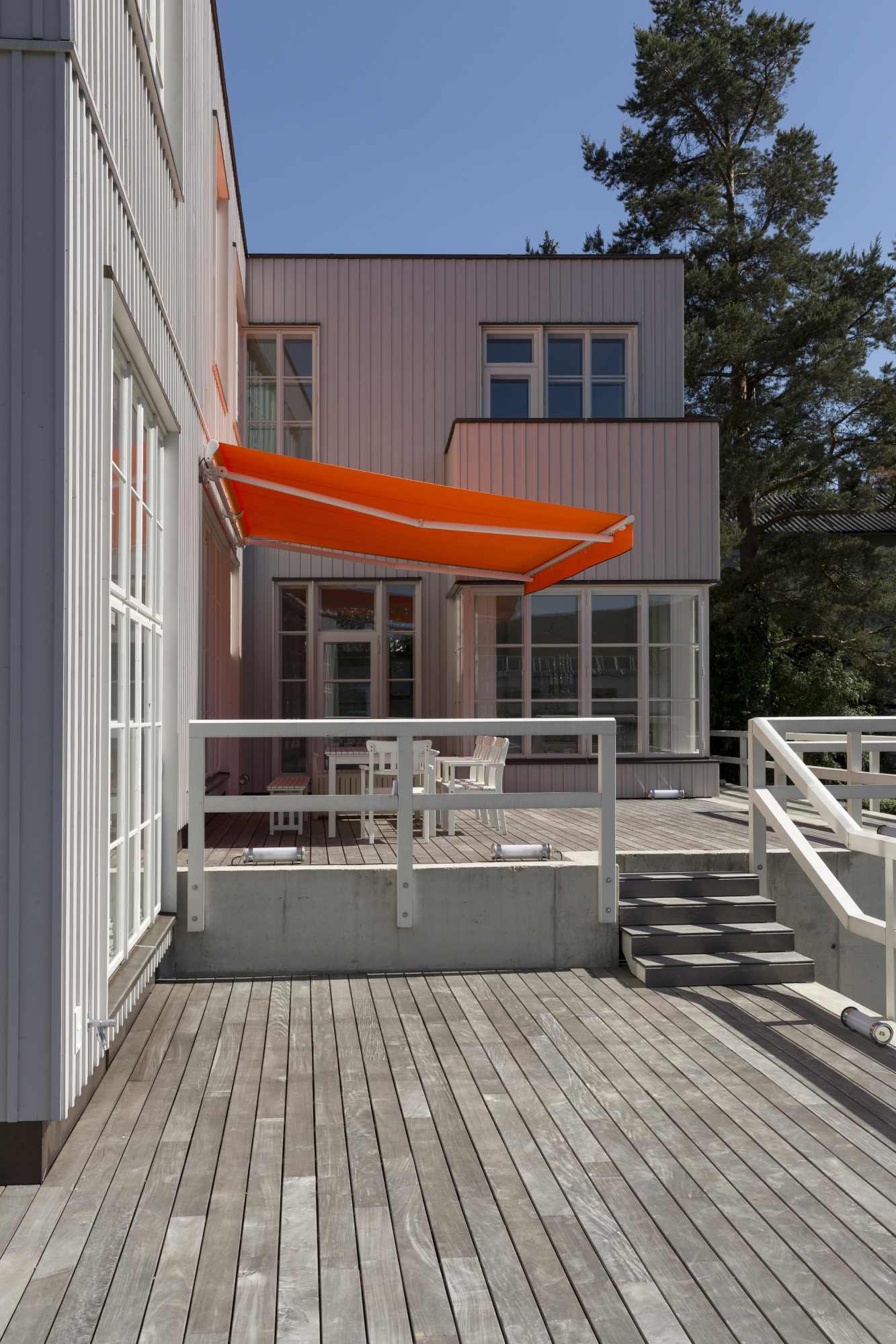 Terrasse mit orangefarbener Markise und Glasfront