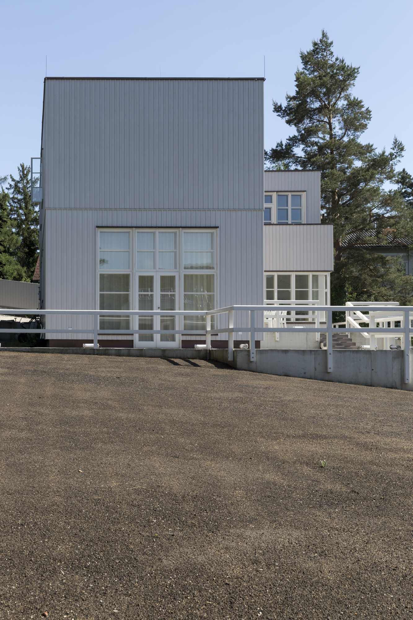 Auffahrt mit Blick auf weiße Villa und Fensterfront