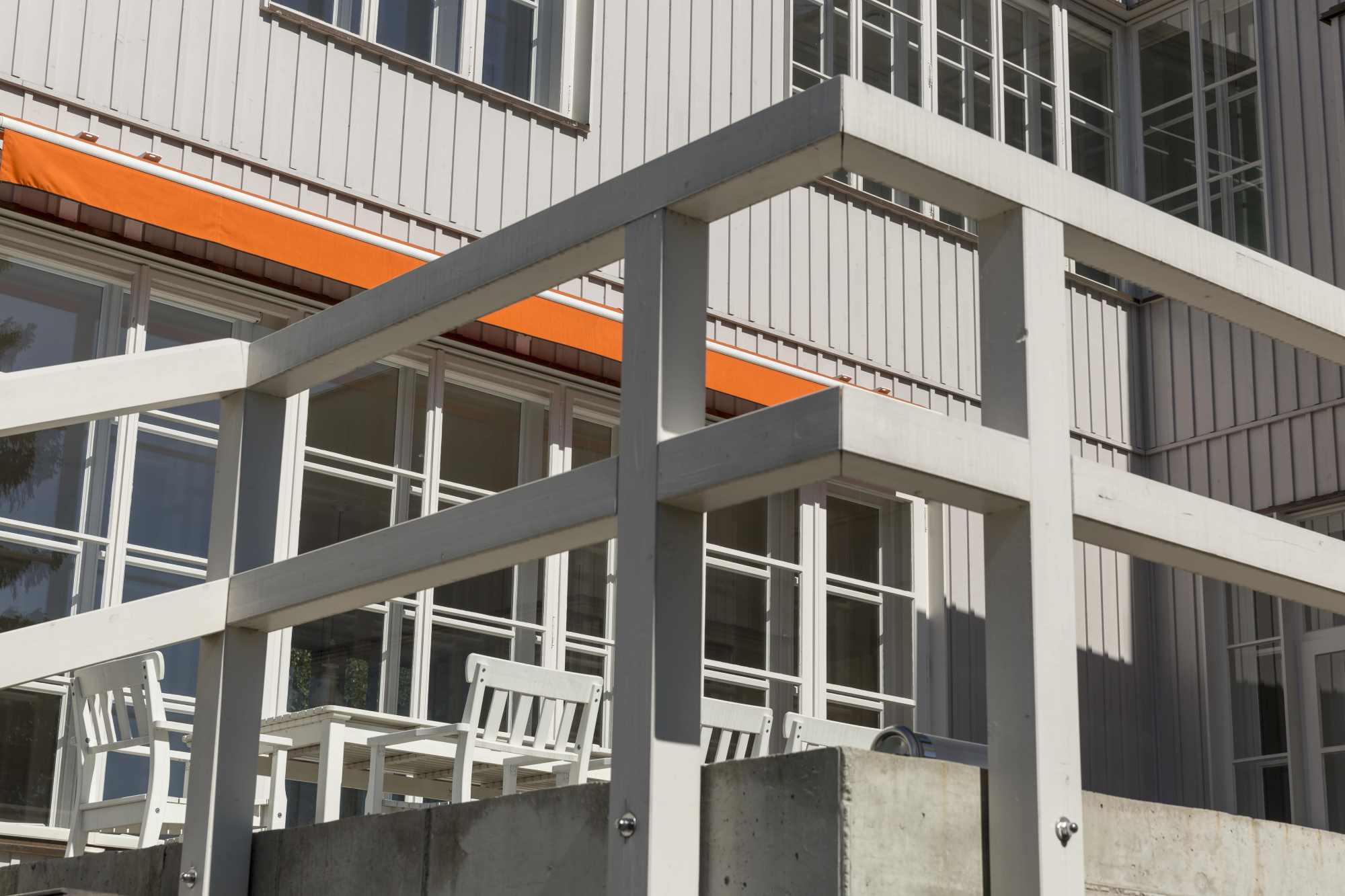 Außenansicht mit Balkon, weißen Stützen und Holzverkleidung