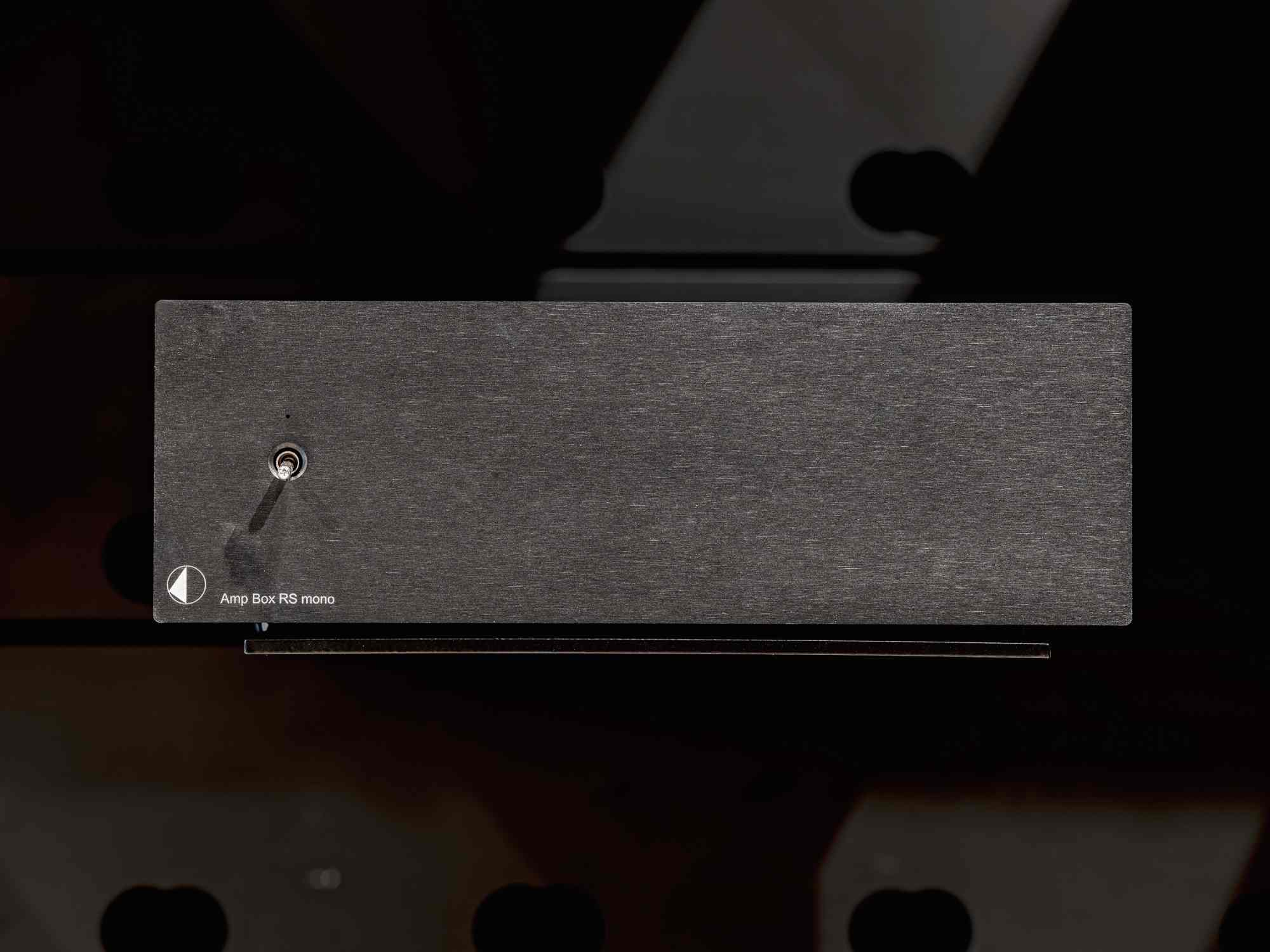 Detailaufnahme einer rechteckigen Metalltafel an einer dunklen Oberfläche.