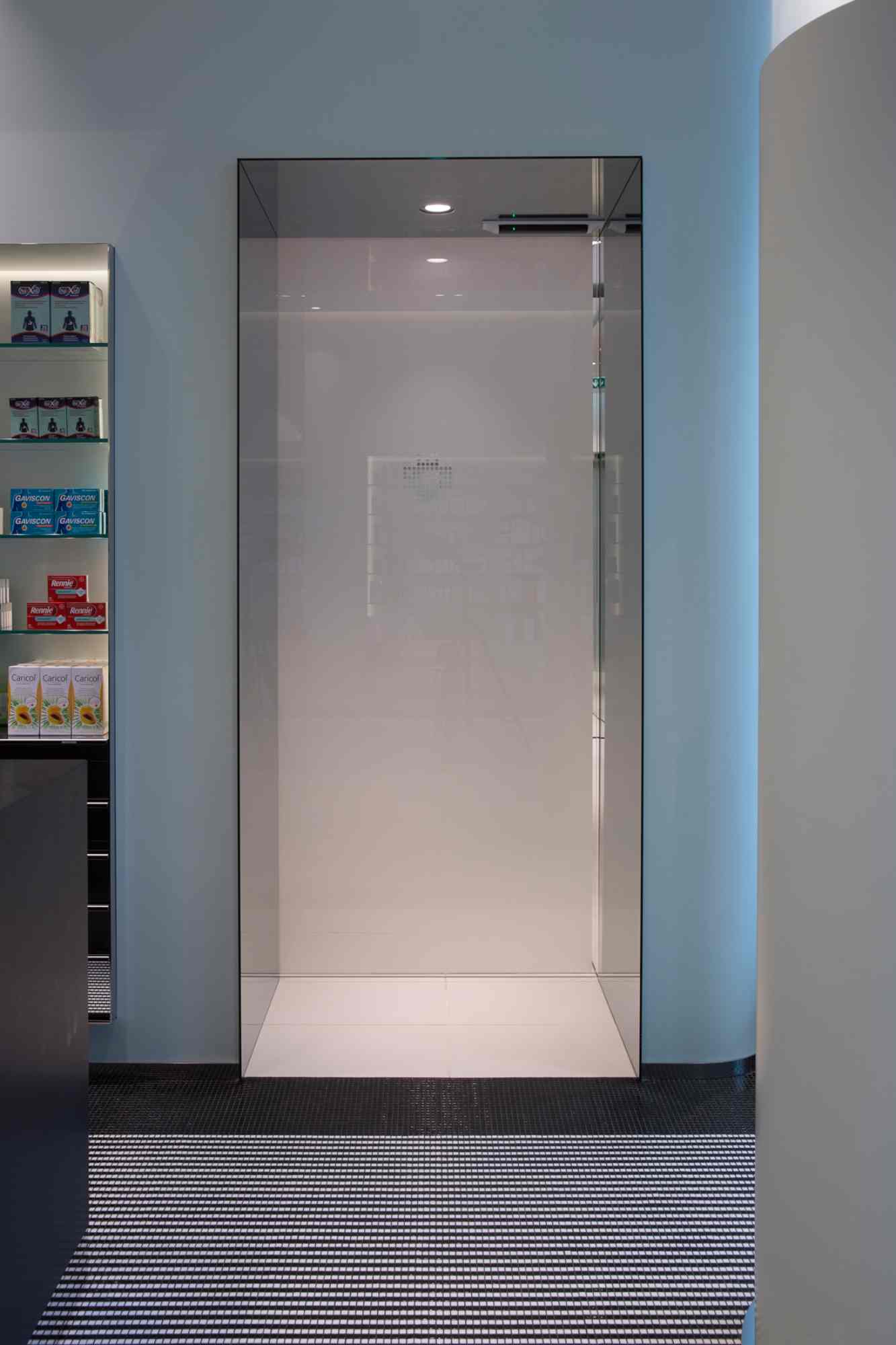 Glasvitrine mit moderner Beleuchtung im Apothekeninnenraum.