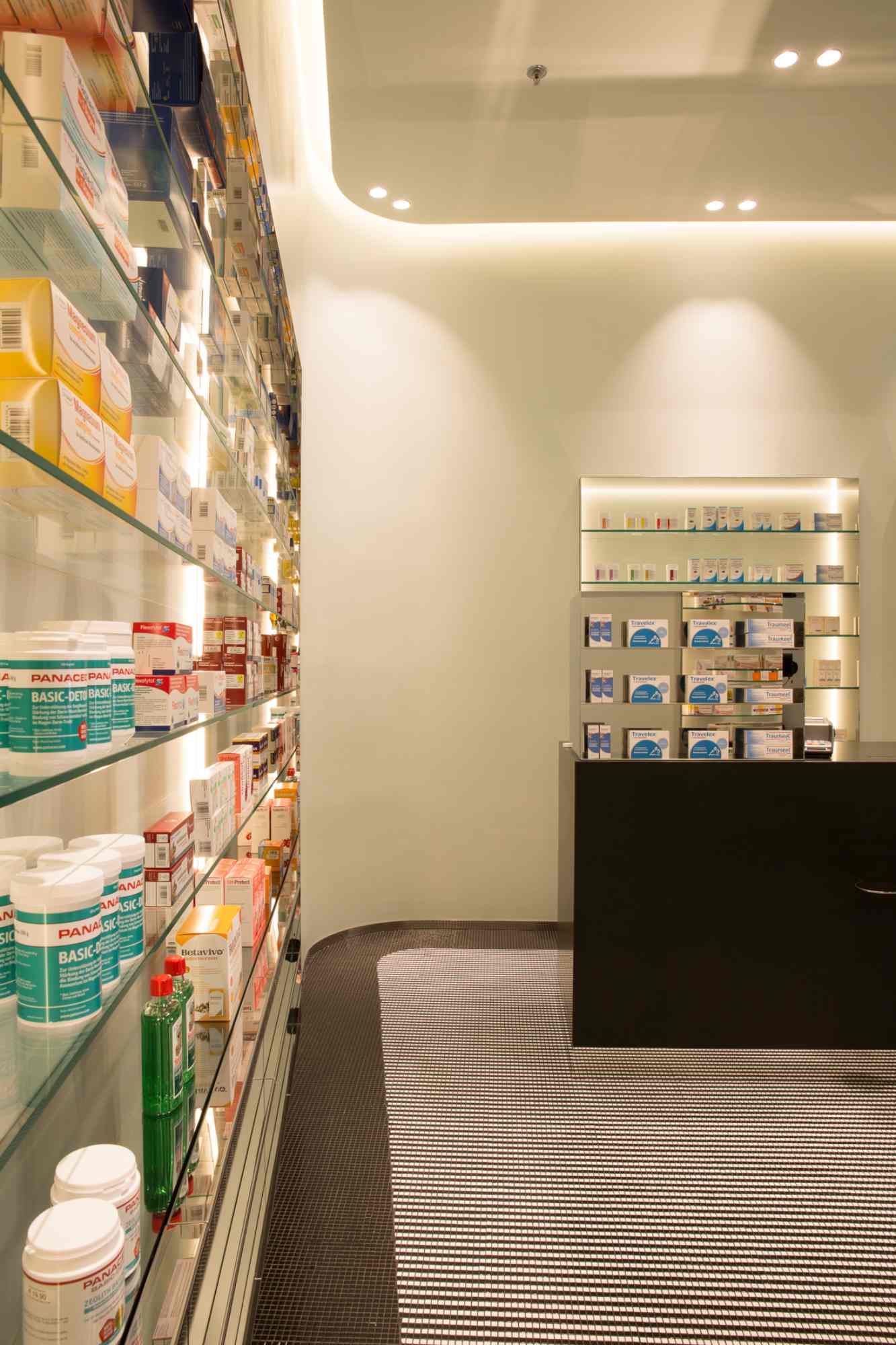 Seitliche Regalwand mit Kosmetik- und Pflegeartikeln in heller Apotheke.