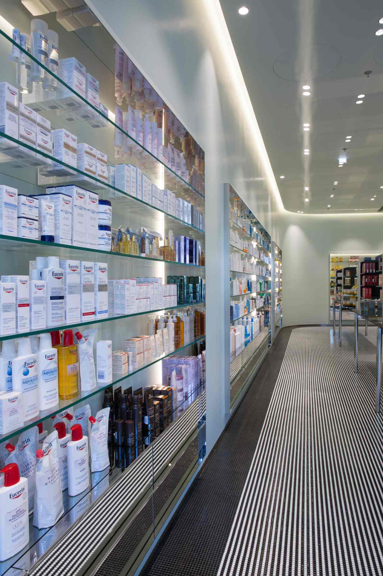 Regalwand mit zahlreichen Medikamenten und Pflegeprodukten in heller Apotheke.