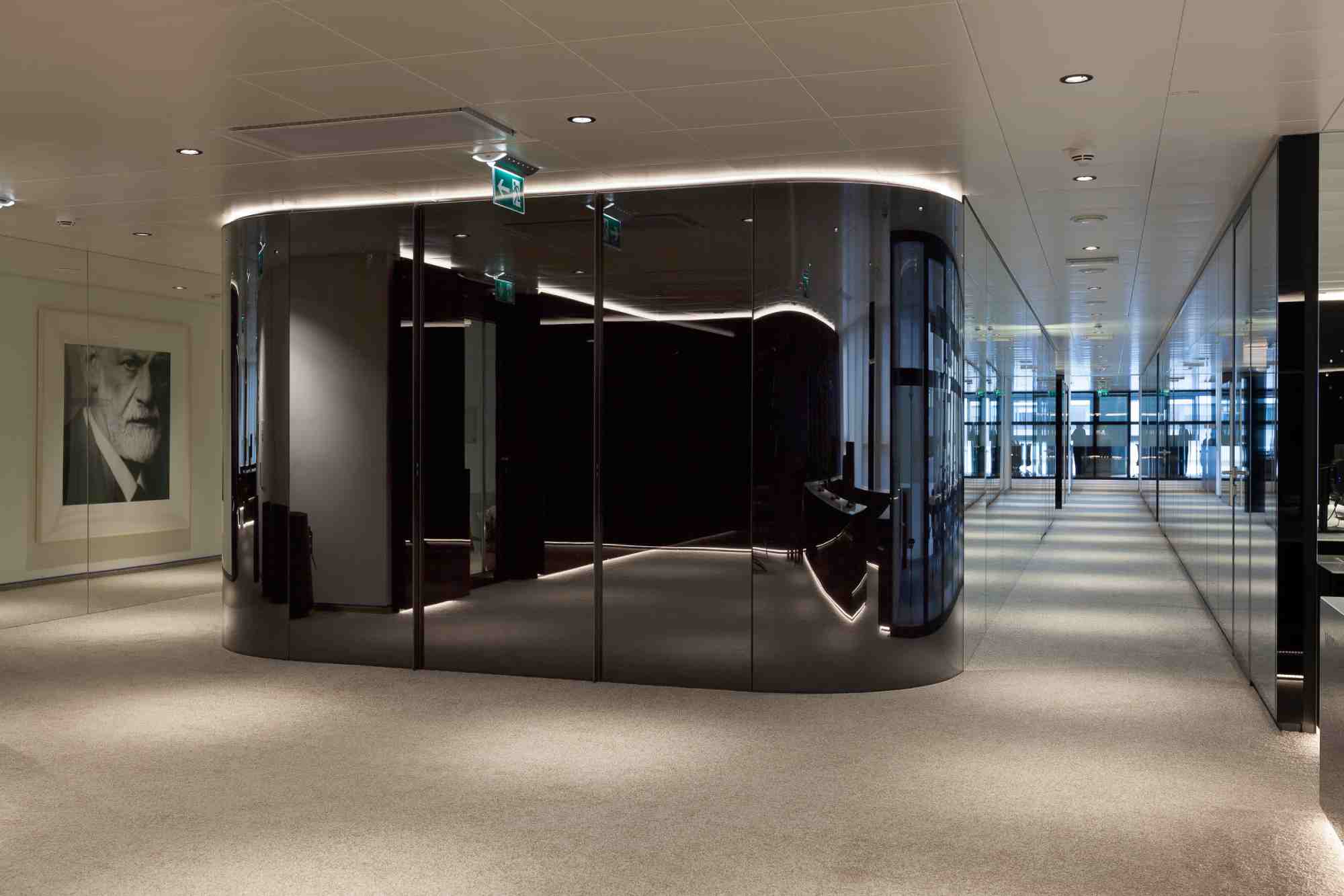 Geschwungene Wand mit dunkler Glasoberfläche im Eingangsbereich Wien Tourismus.