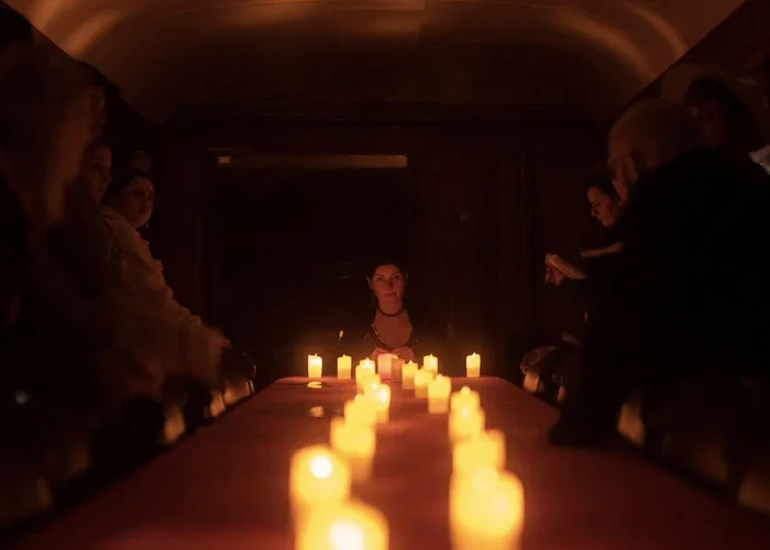 Des personnes encapuchonnées rassemblées autour d'une grande table à la lumière des bougies