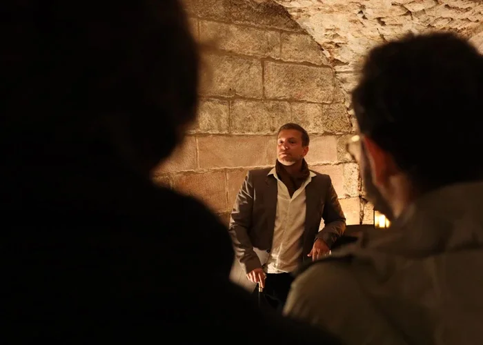 Le public-enquêteur écoute un acteur se présenter dans les caveaux du château