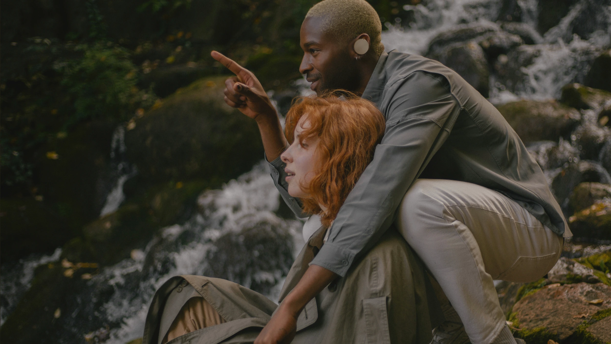 Young woman with braided hair wearing a black hoodie and iyO One standing in a dimly lit urban alley