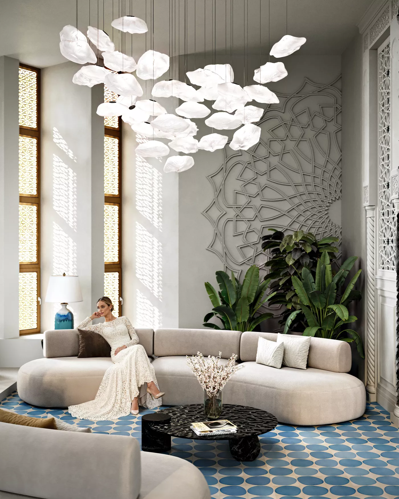 Woman in elegant white lace dress sitting on a beige curved sofa in a modern living room with decorative wall art, large green plants, and a black round coffee table on blue patterned floor tiles.