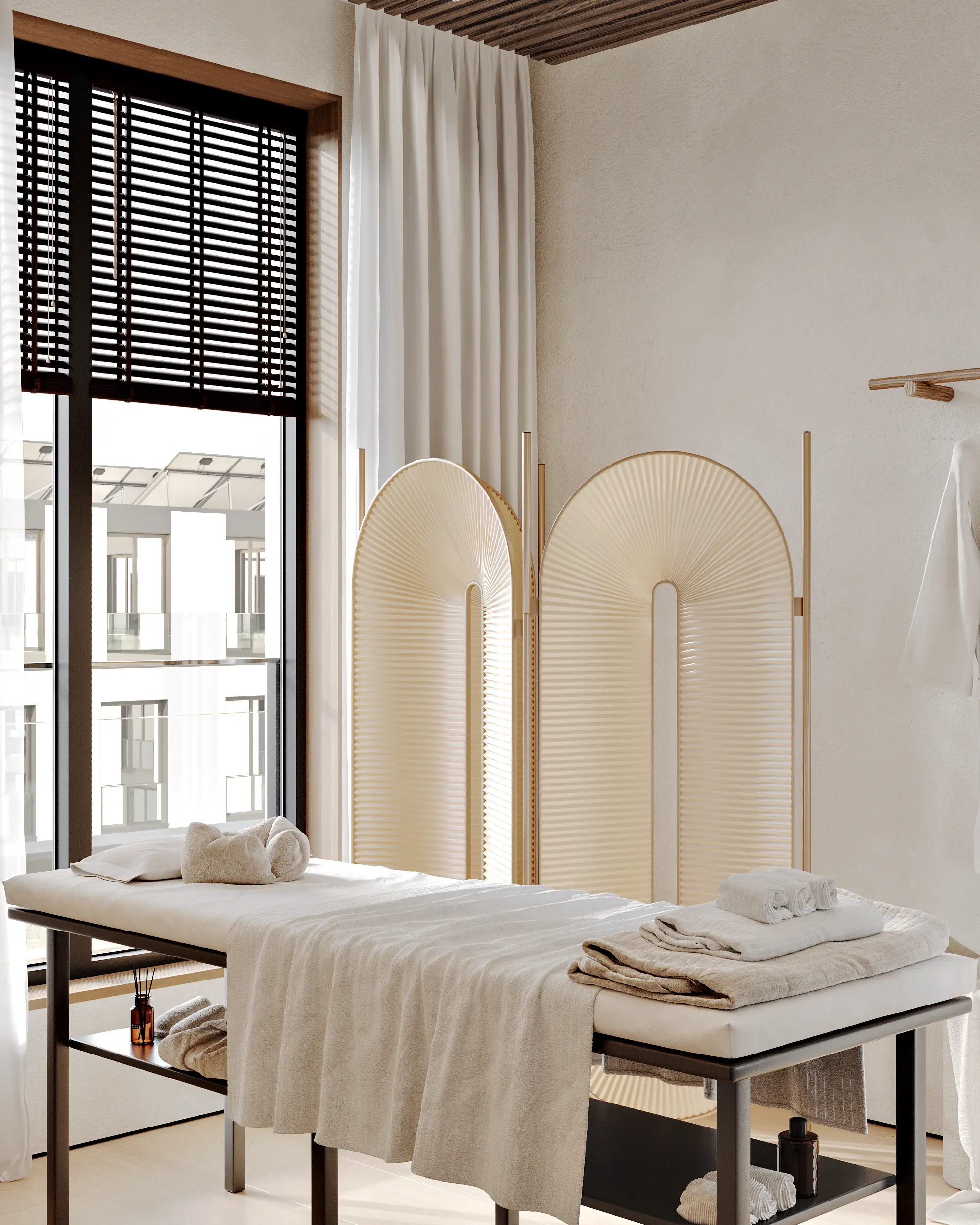 Modern spa treatment room featuring a massage table with fresh towels and a beige pleated room divider.