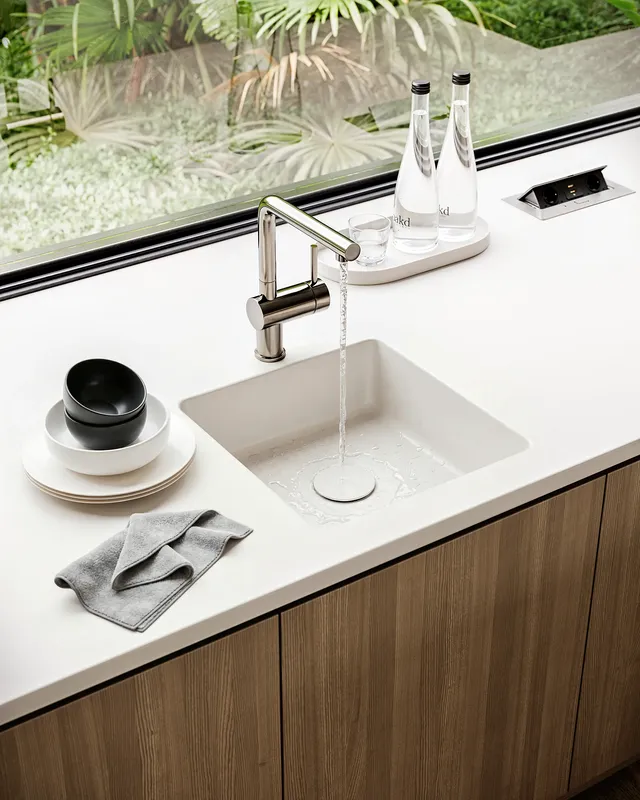 Kitchen sink area with decor situated by a window overlooking the backyard.