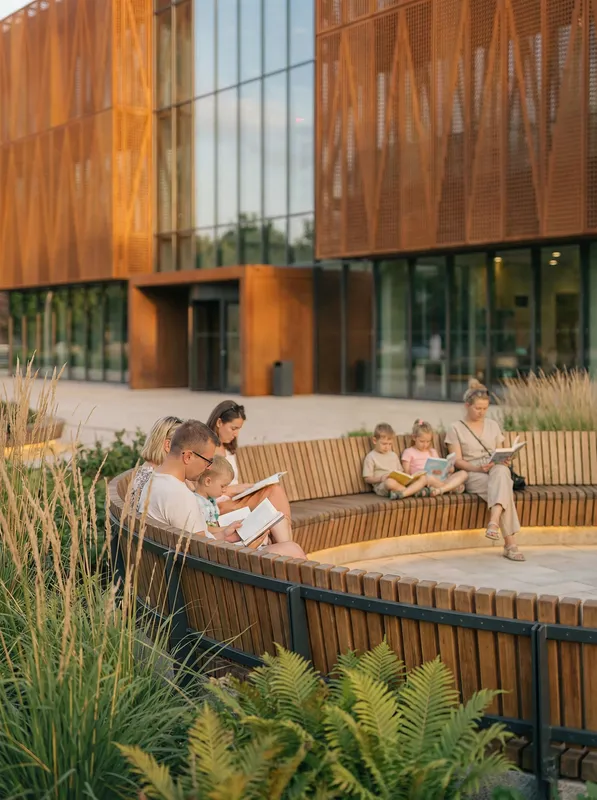 Circular benches near a community center with people reading.