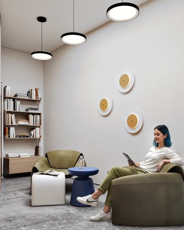 Woman sitting in an armchair in a stylish reading lounge with bookshelves and a coffee table.