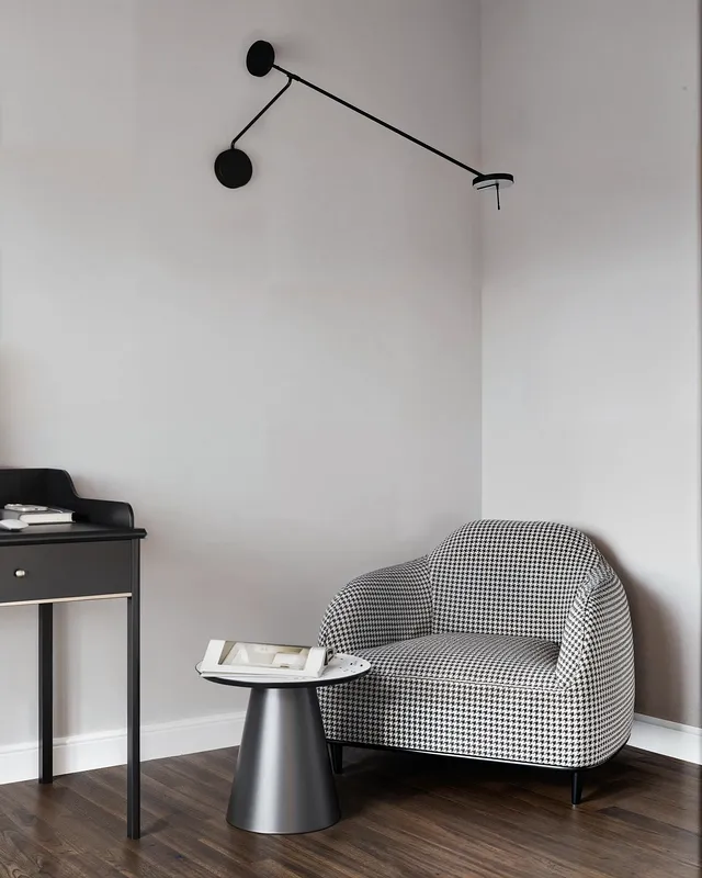 Reading corner featuring an armchair, side table, and wall sconce.