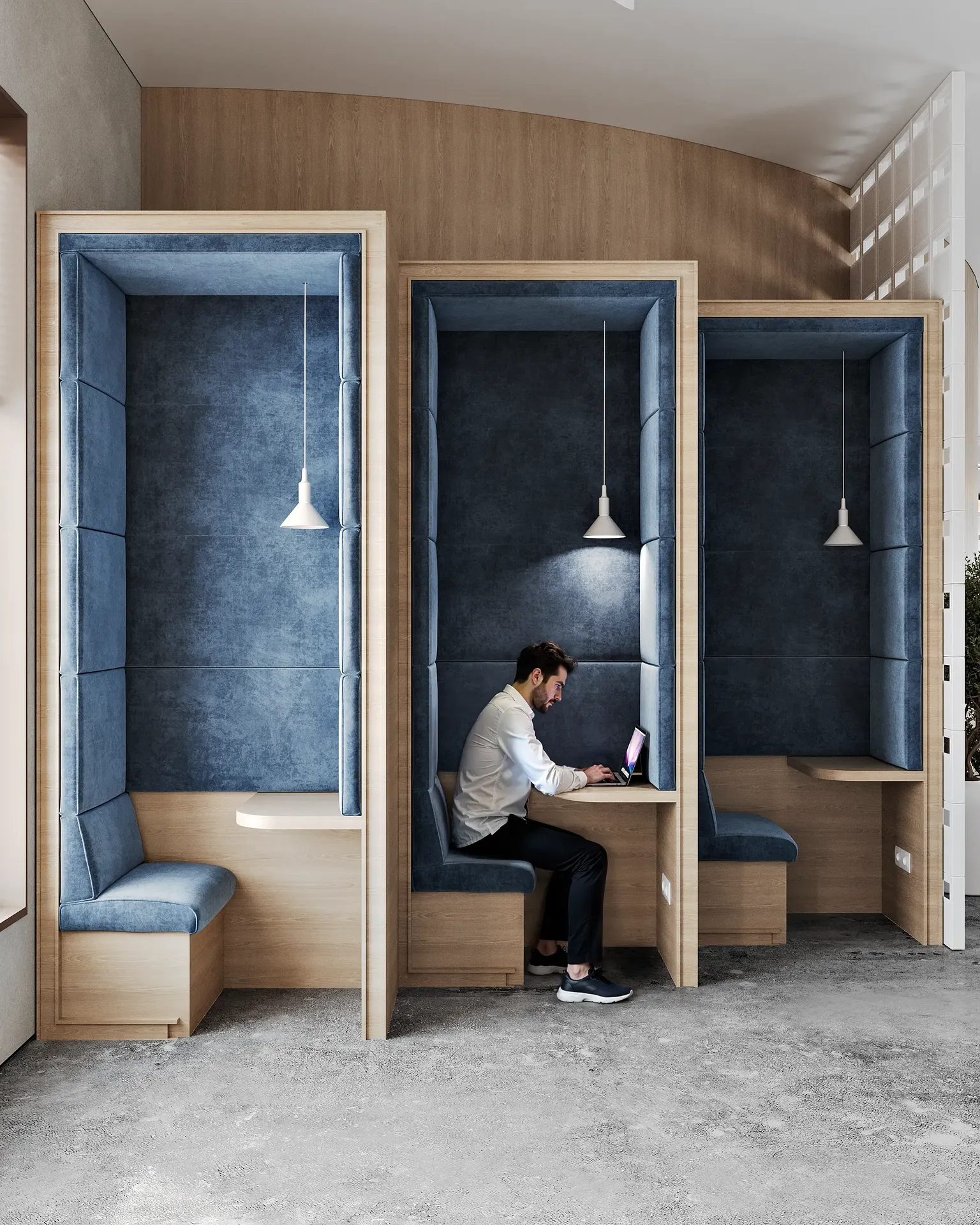 Man working on a laptop inside a private, blue upholstered meeting booth.