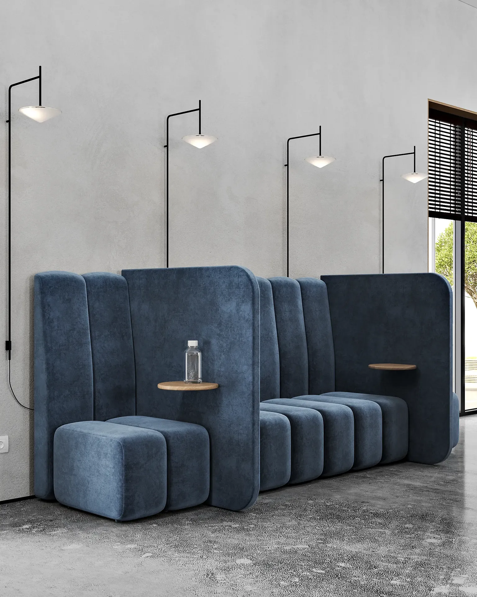 Collaborative lounge area with a long blue sofa, side tables, and ambient wall sconces.