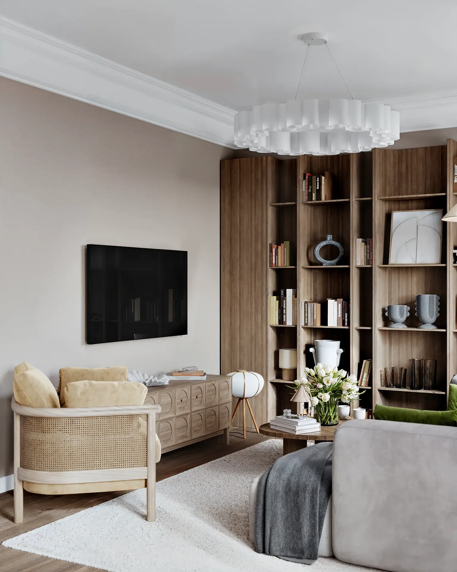 Angled view of a TV zone with a media unit, shelving, and armchair.