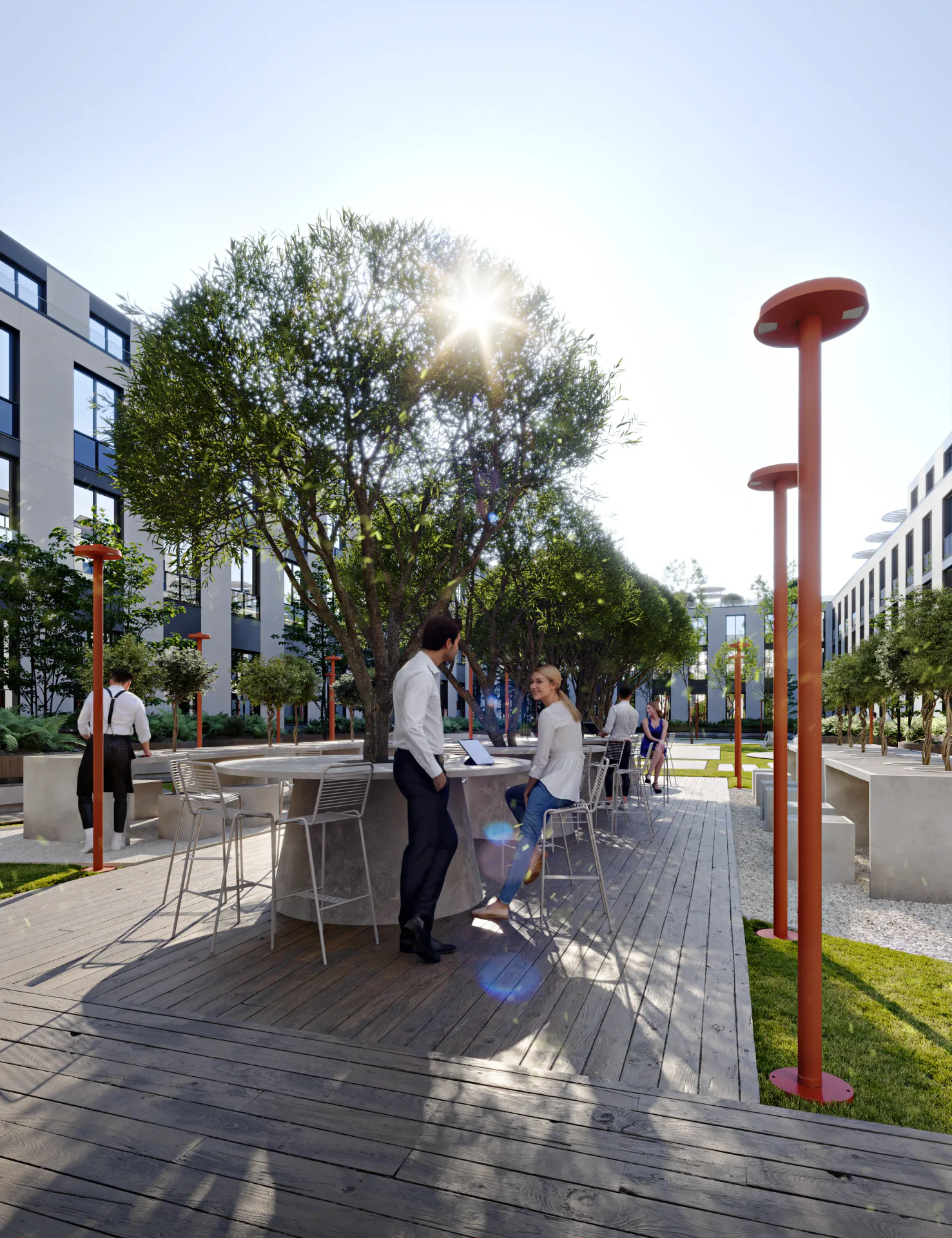 Frontal view of the community plaza, showing people relaxing and working at tables under trees.