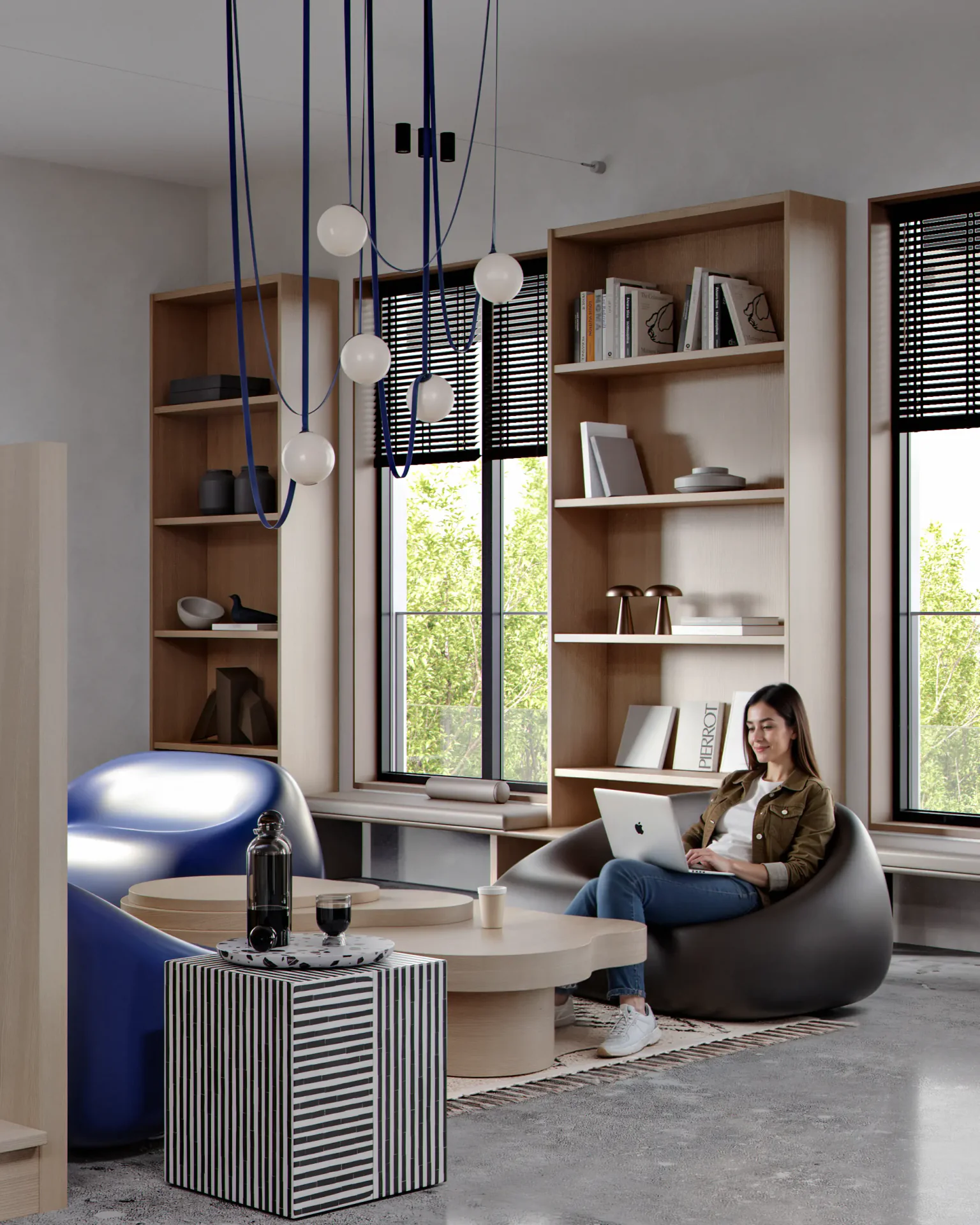 Woman working on a laptop in a casual work lounge with armchairs by a bookshelf.
