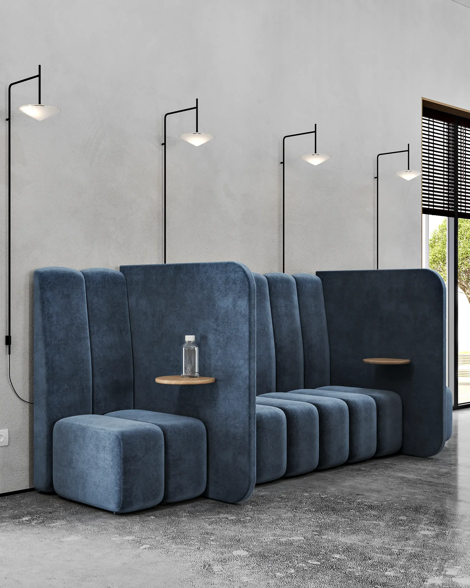 Collaborative lounge area with a long blue sofa, side tables, and ambient wall sconces.