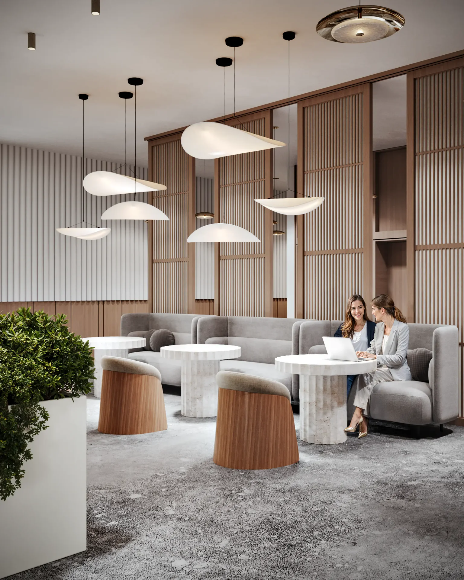 Two women collaborating in a modern elevator lobby lounge, featuring sofas and wood partitions.