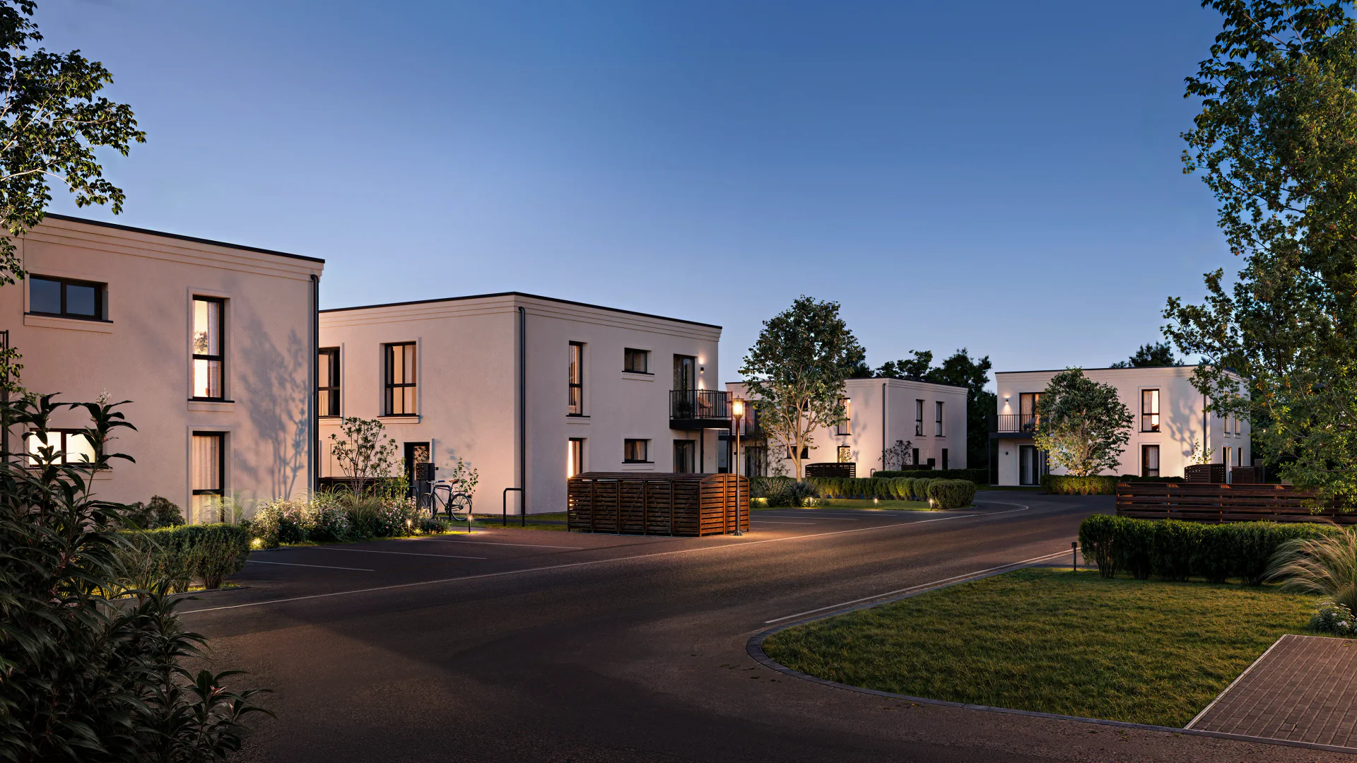Evening street view of a residential complex with illuminated facades and landscaping.