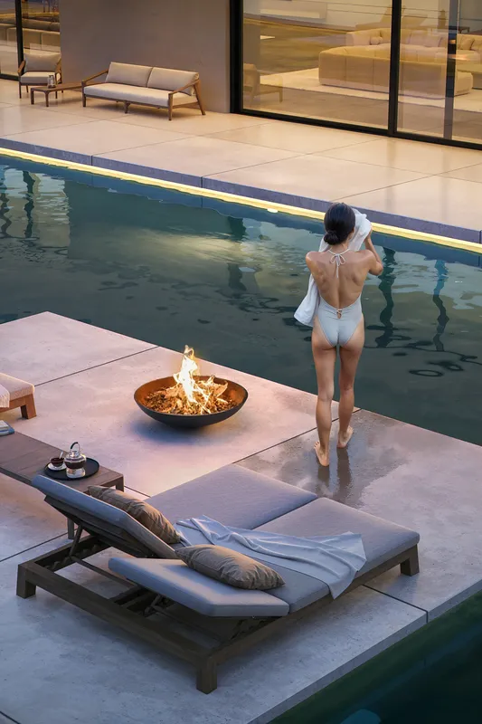 Femme se détendant près d’une piscine avec chaises longues.