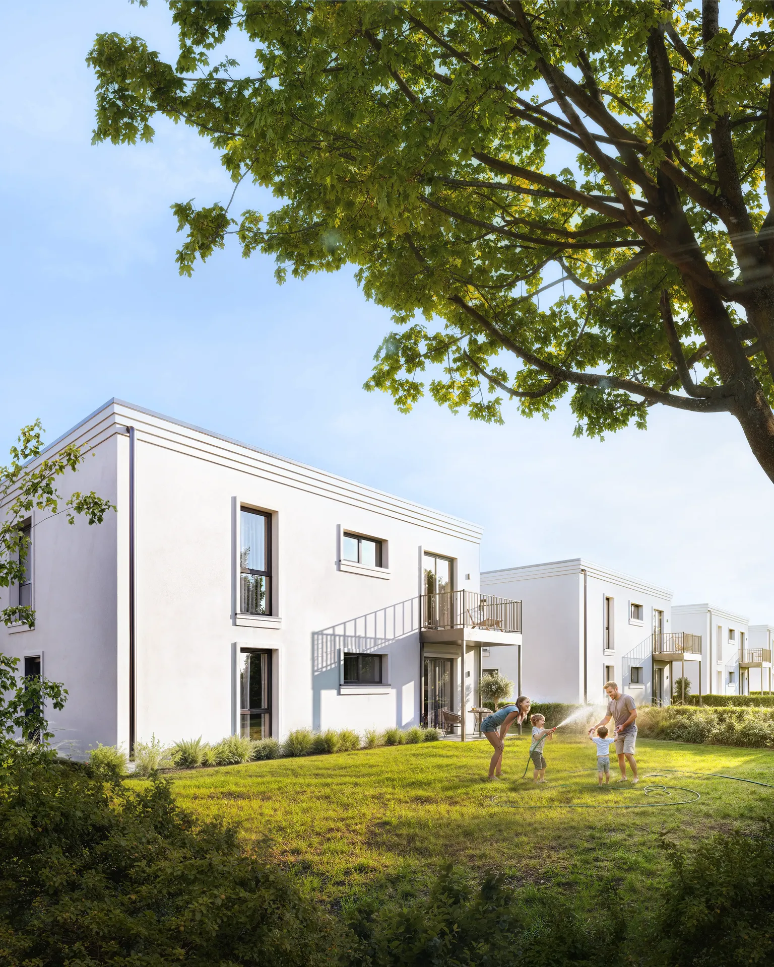 Famille se rafraîchir avec des jeux d'eau dans la cour ensoleillée d'une résidence.