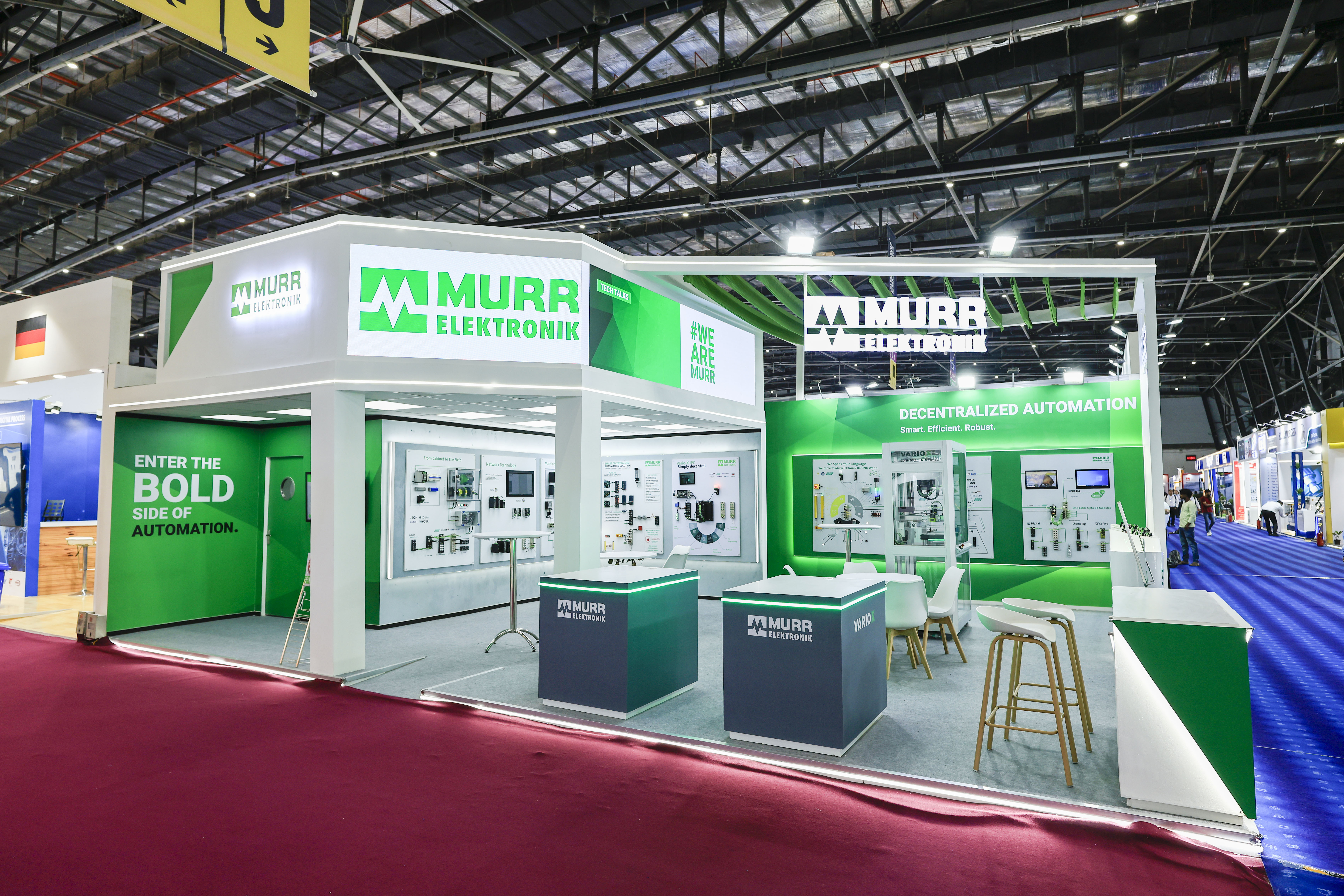 Murr Elektronik exhibition stand by Blues N Coppers, with green branding, product wall displays, and a meeting area