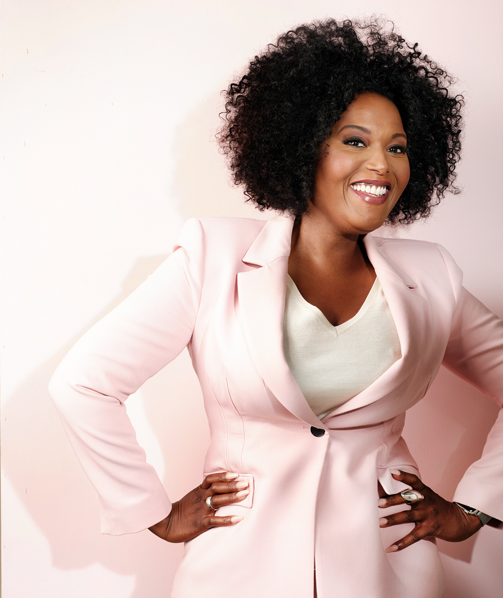 Denice Dest in roze pak lachend als Innervoice Activator en coach